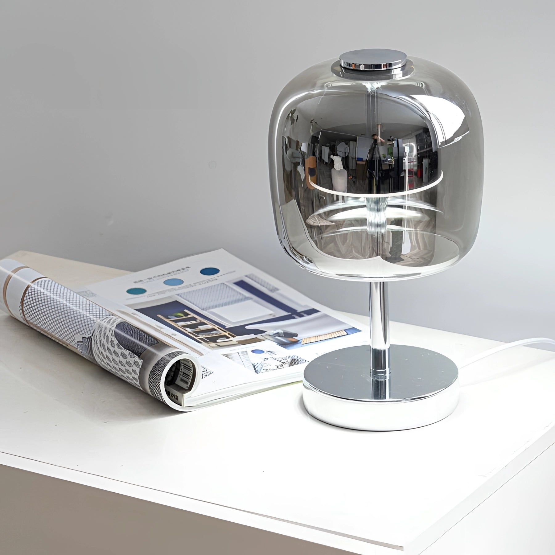 A modern LED glass lamp featuring a transparent shade and a sleek chrome base, positioned on a table.