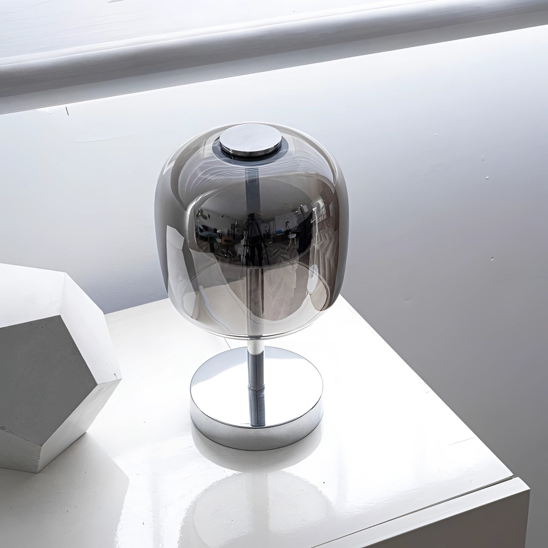 Modern LED glass lamp with a chrome base and transparent shade placed on a table.
