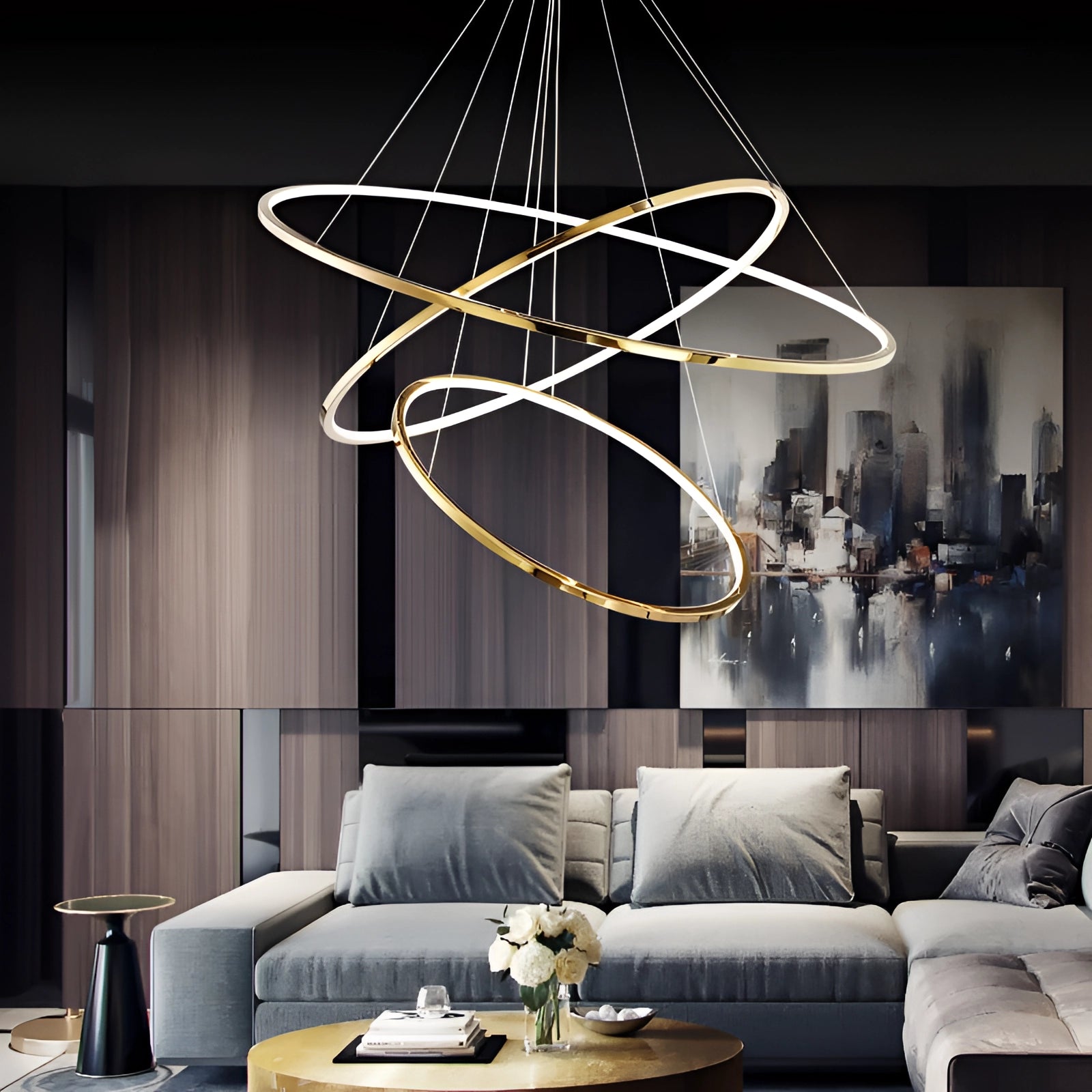 Modern LED Orbital Chandelier with 3 tiers hanging above a contemporary living room setting featuring a black couch and a rectangular table, showcasing luxury interior design elements.