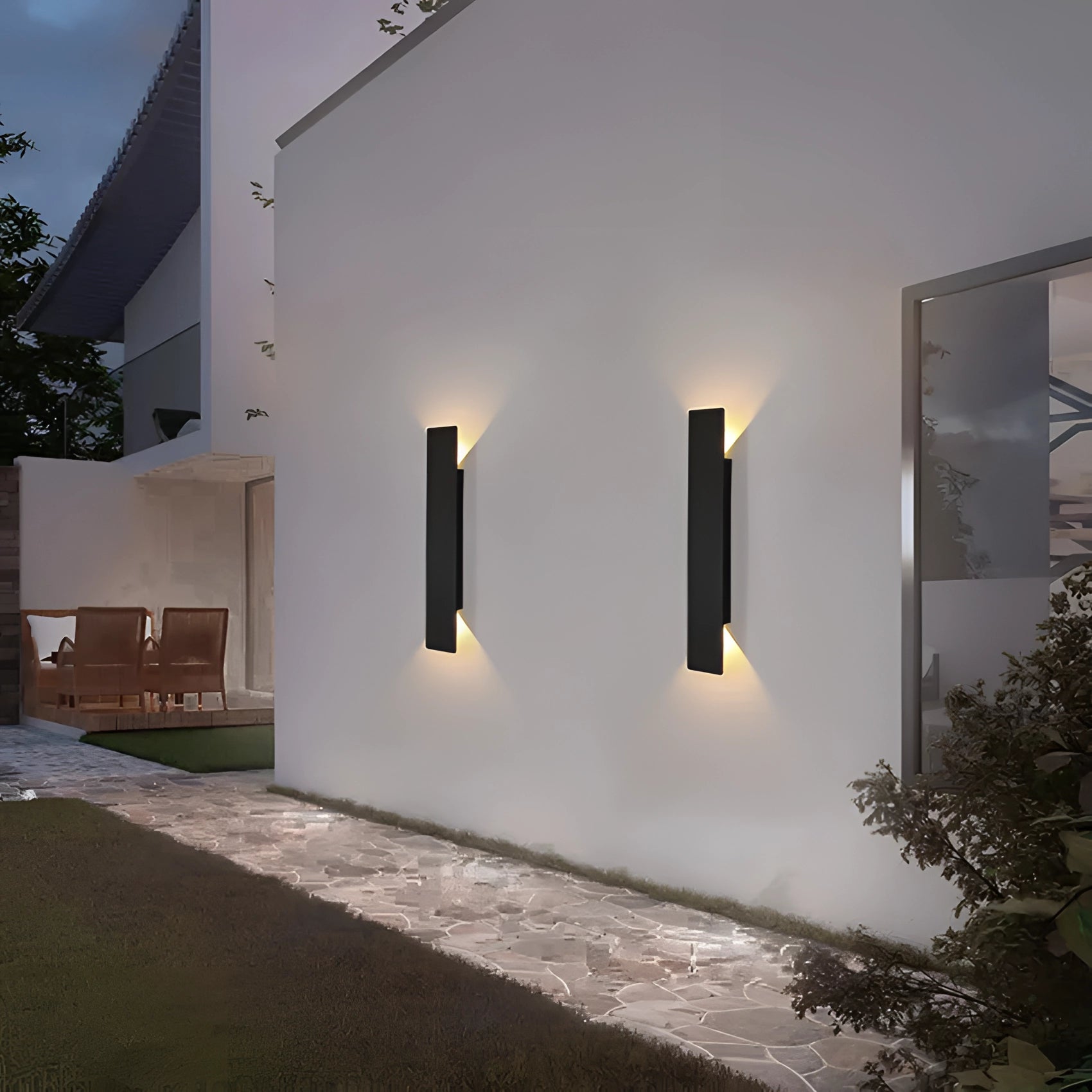 Modern LED outdoor wall light mounted on a building facade, surrounded by urban landscaping with visible plants and windows, under a clear sky.
