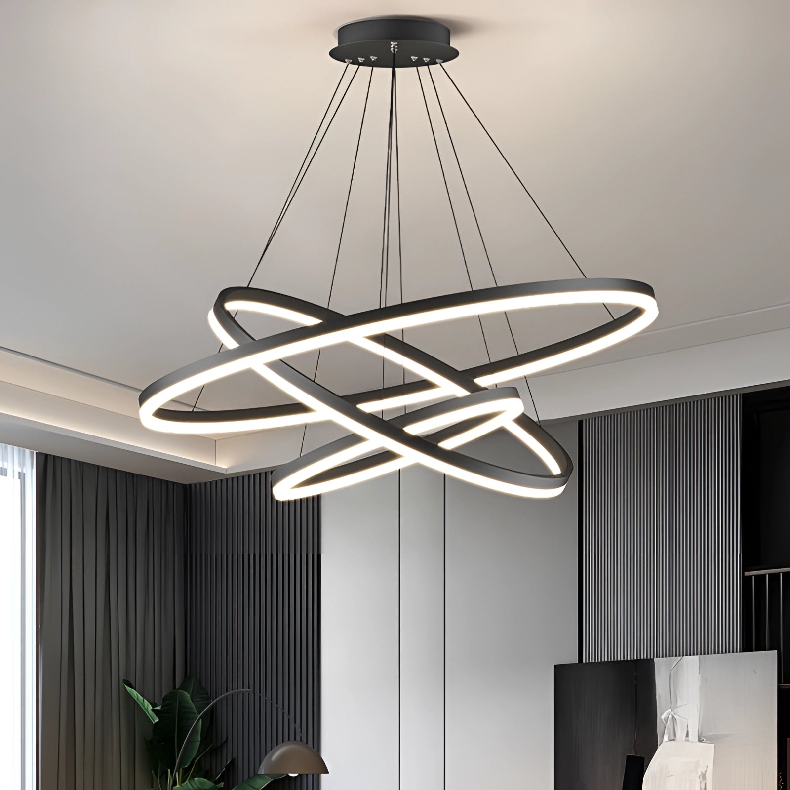 Modern LED pendant light with a circular orbit design, featuring three rings in sizes 23.5", 31.5", and 39". The chandelier is dimmable and shown in a contemporary interior setting, highlighting its sleek architecture and warm ambient lighting.