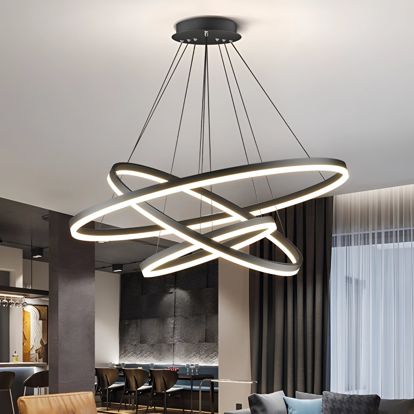 Modern LED pendant light with a circular chandelier and orbit design, featuring three rings measuring 16, 23.5, and 31.5 inches, displayed in an interior setting with dimmable lighting effects, complementing the contemporary furniture and decor.