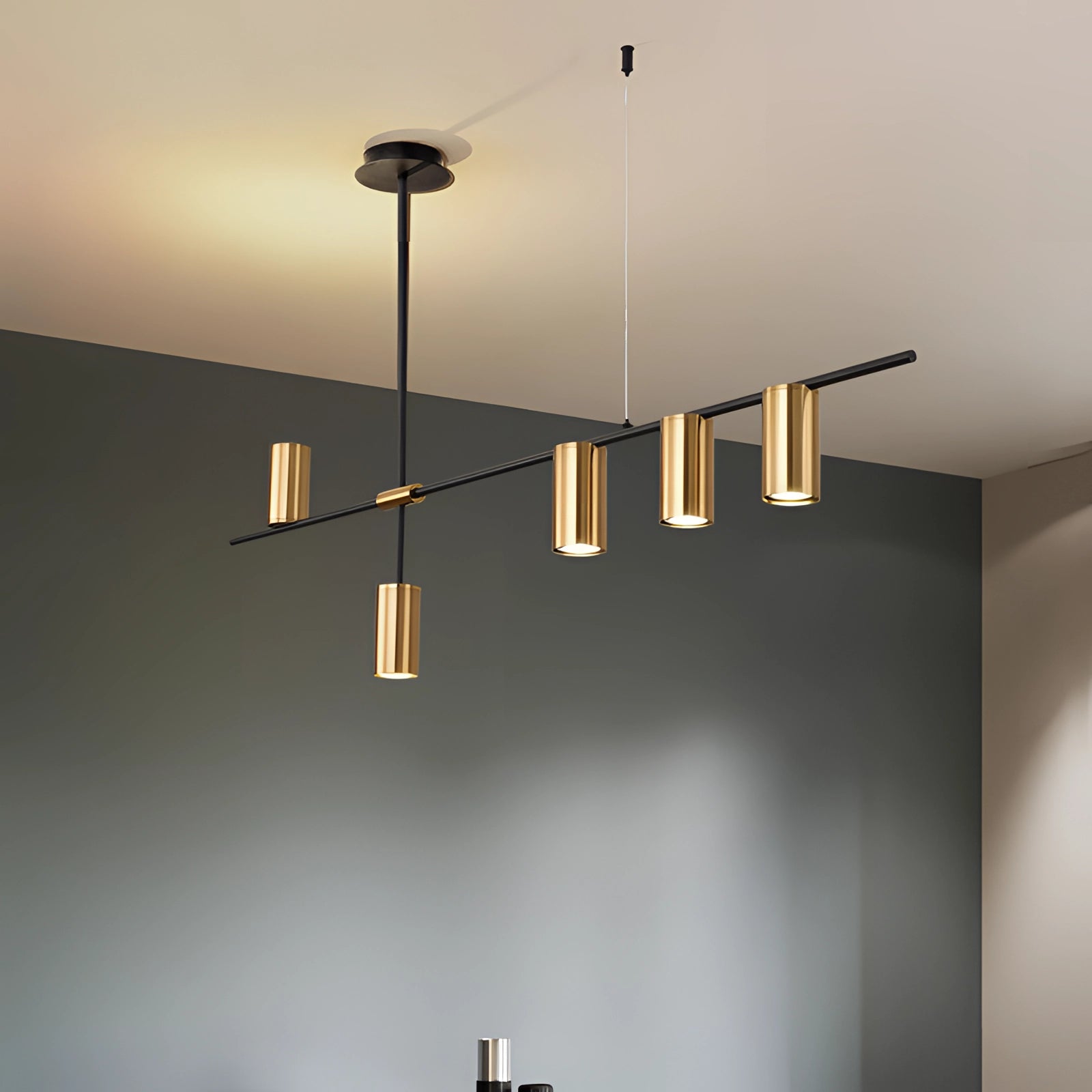 Modern LED pendant light with a matte black and gold finish, hanging from a ceiling, illuminating a contemporary kitchen space.
