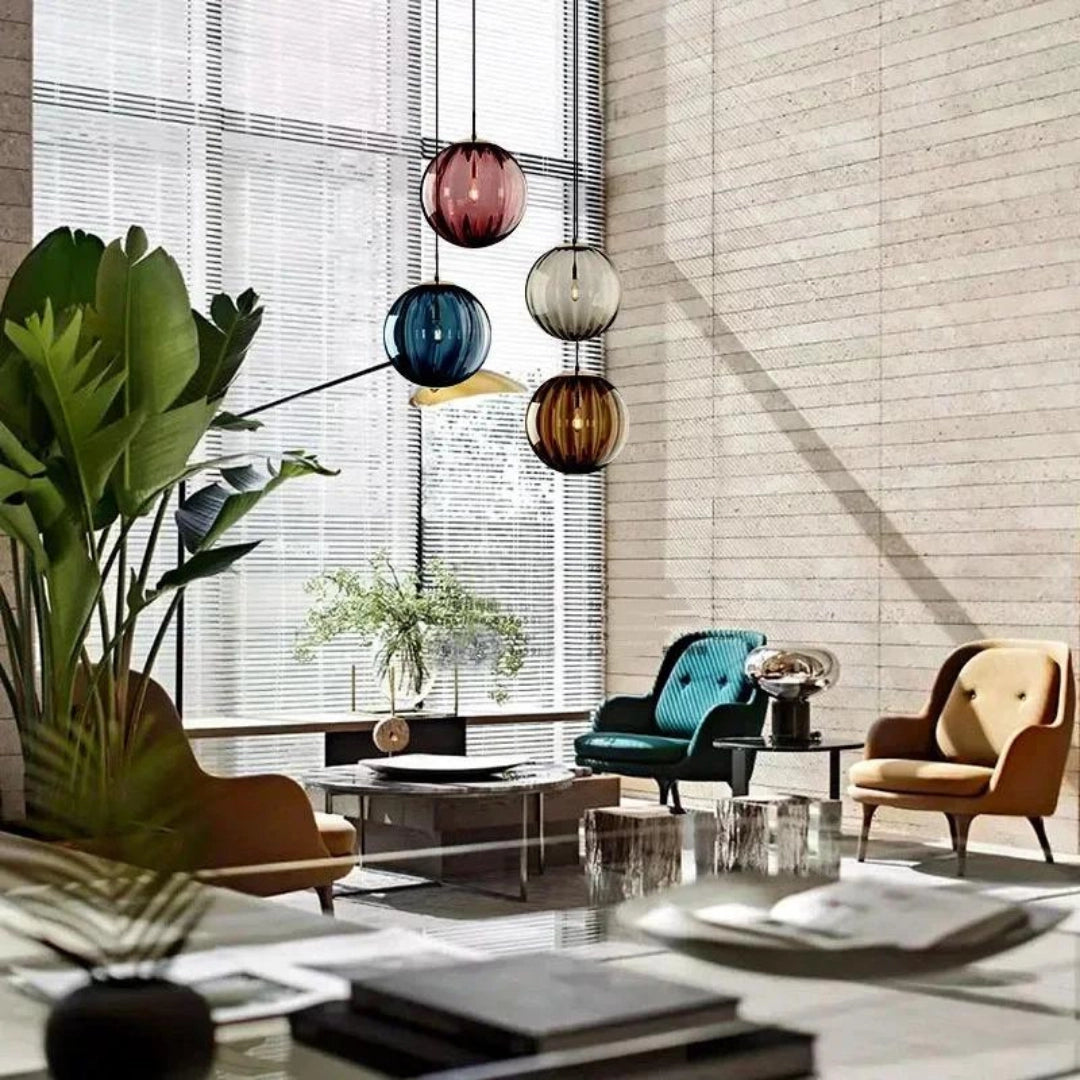 Modern LED pendant lights with designer glass shades hanging in a stylish living room setting, featuring wooden furniture, green plants, large windows, and a sleek table.