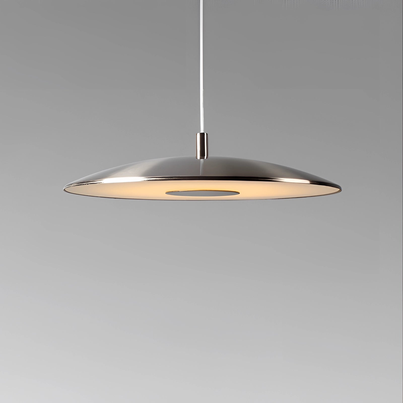 Modern silver LED pendant lights hanging from the ceiling above a dining table, featuring a sleek circular design and a stylish metal finish.