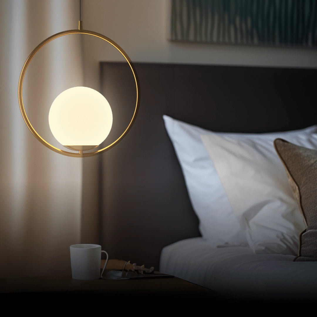Modern LED round bedside lamp in a minimalist design with a gold finish, emitting a cold white light. The lamp is placed on a wooden surface, complementing the interior decor with its circular shape.