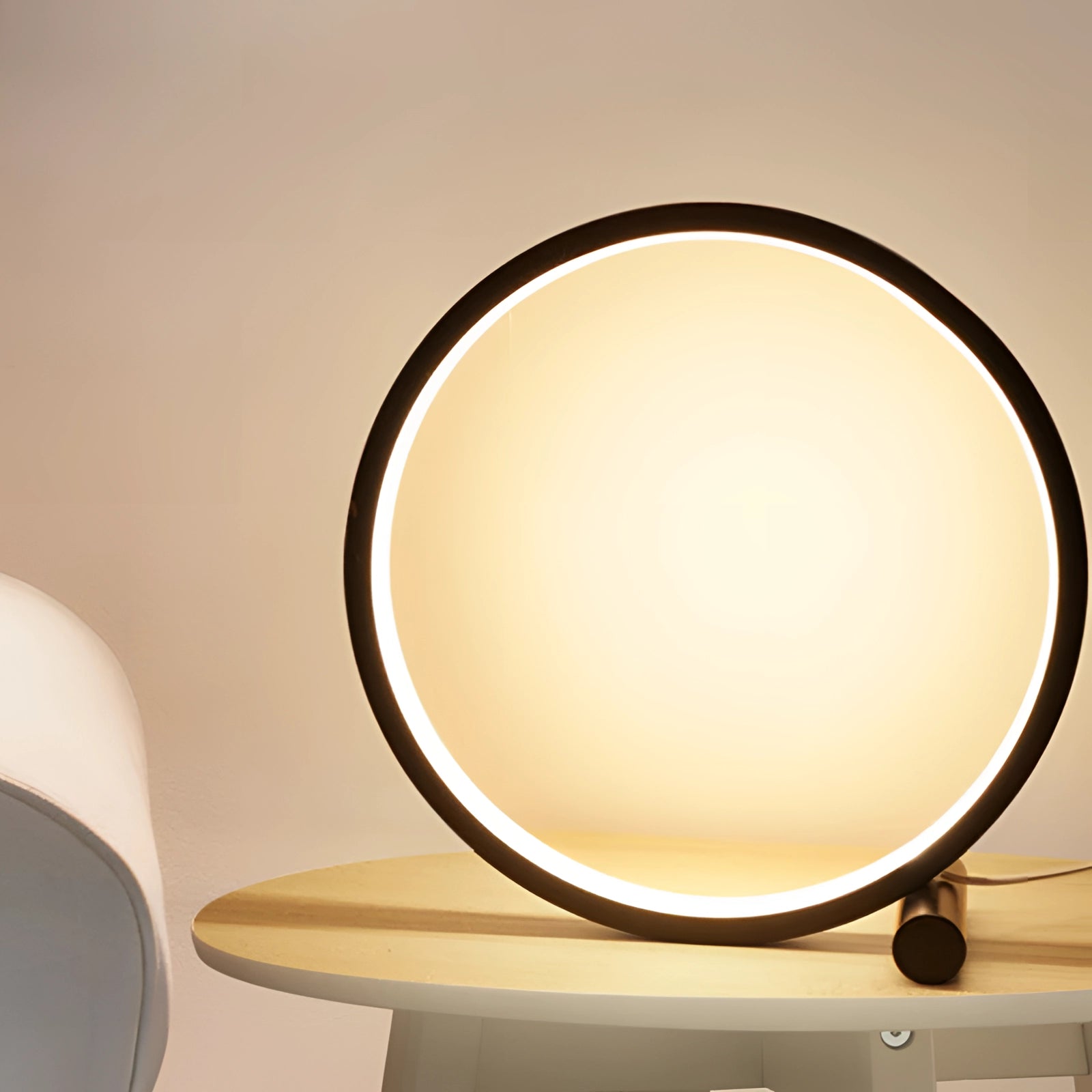 Modern LED table lamp with a circular design featuring a minimalist style, emitting warm light, set on a wooden table.