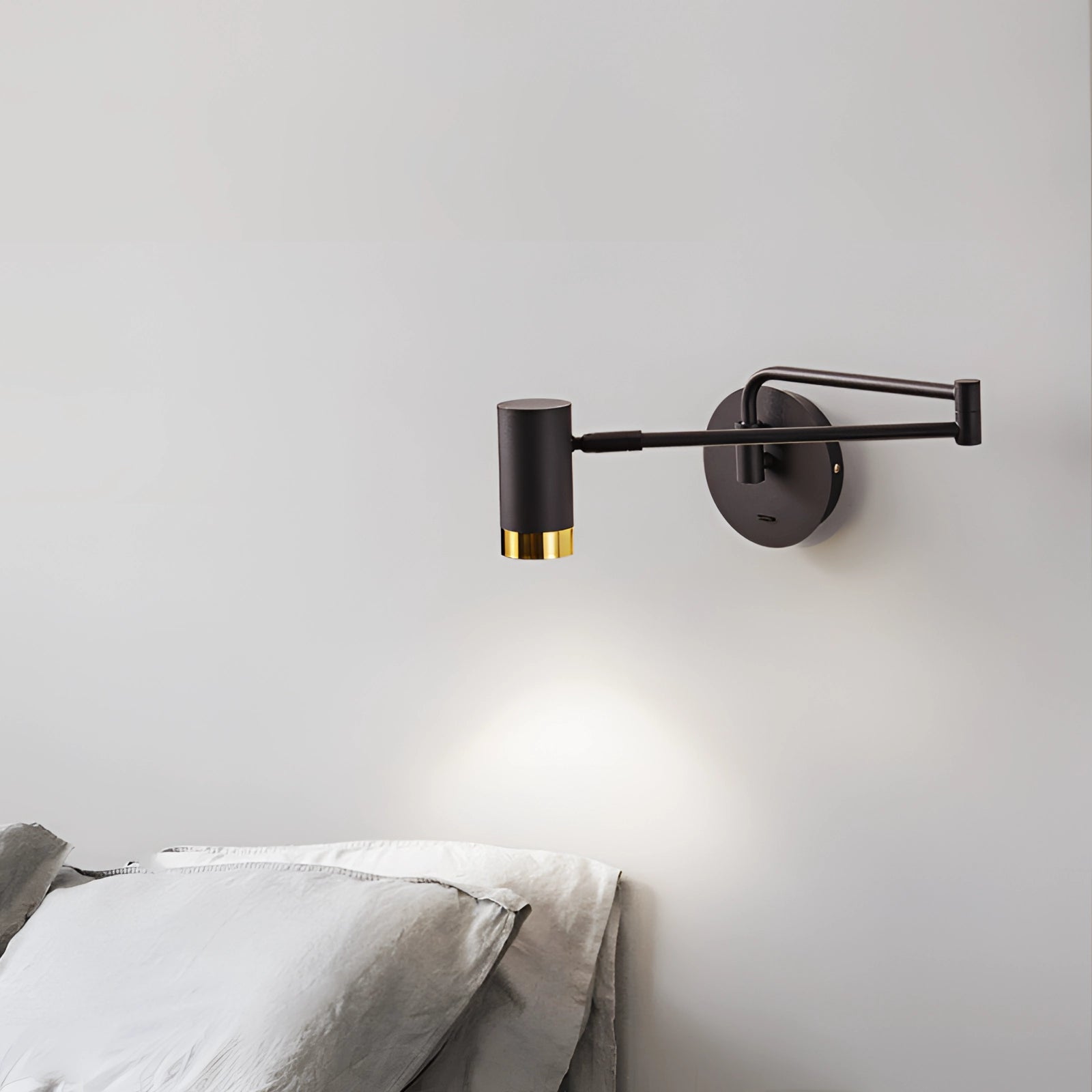 Modern LED wall lamp with an adjustable spotlight in black, featuring sleek white and gold accents, mounted on a wall in a comfortable room setting.