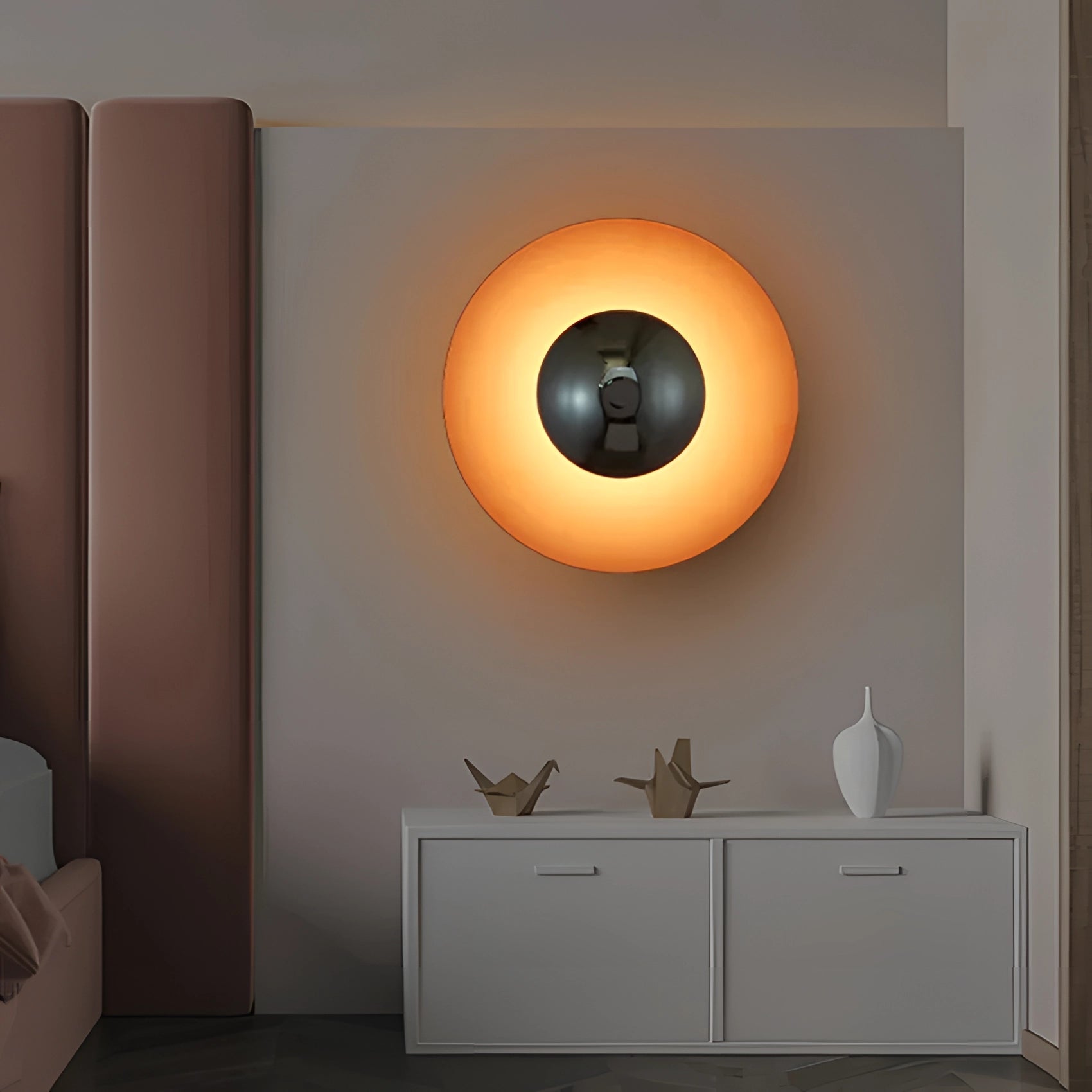 Modern LED wall lamp made of brass, designed as a minimalistic decorative sconce, mounted on a wooden wall in an interior setting. The lamp emits a warm orange glow, complementing the contemporary interior design.