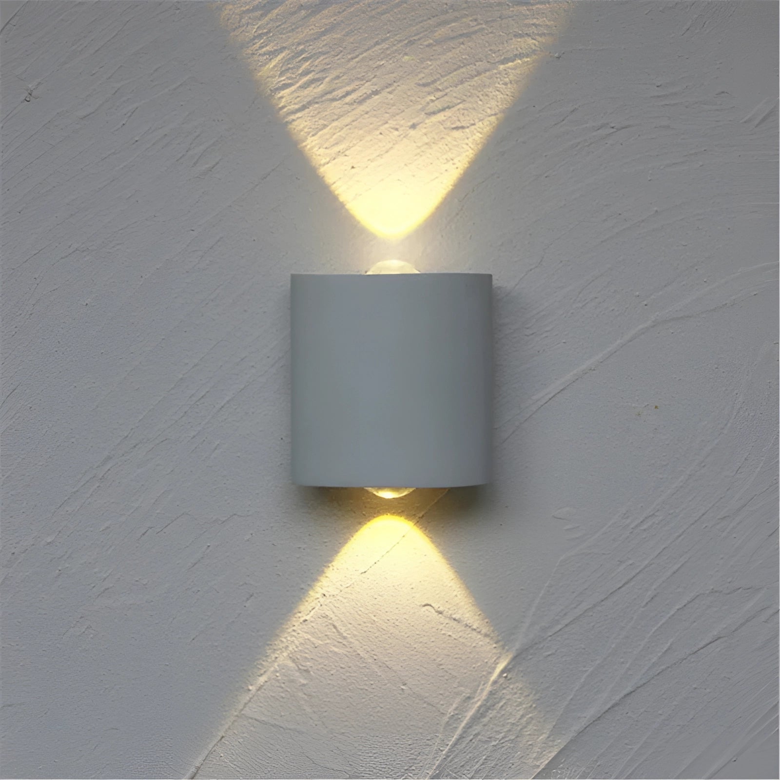 Modern LED wall sconce featuring a geometric cylinder design in white, mounted on a wall, emitting dual beams of light.