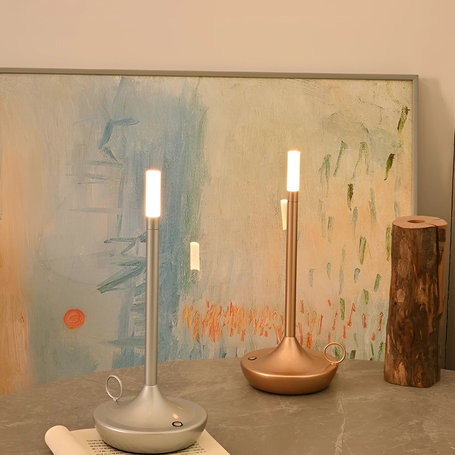 A set of modern luxury metallic candle holders displayed in an elegant home interior setting, featuring a wooden floor, artistic design elements, and sophisticated glass cylinders.