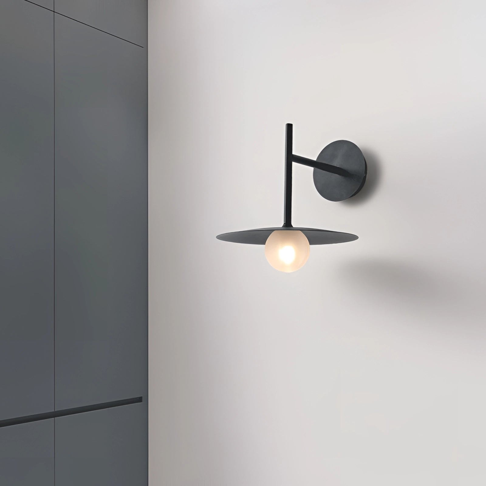 Modern matte black minimalist wall sconce mounted on a wall, designed for bedroom and hallway lighting, with sleek geometric lines and a soft ambient glow.