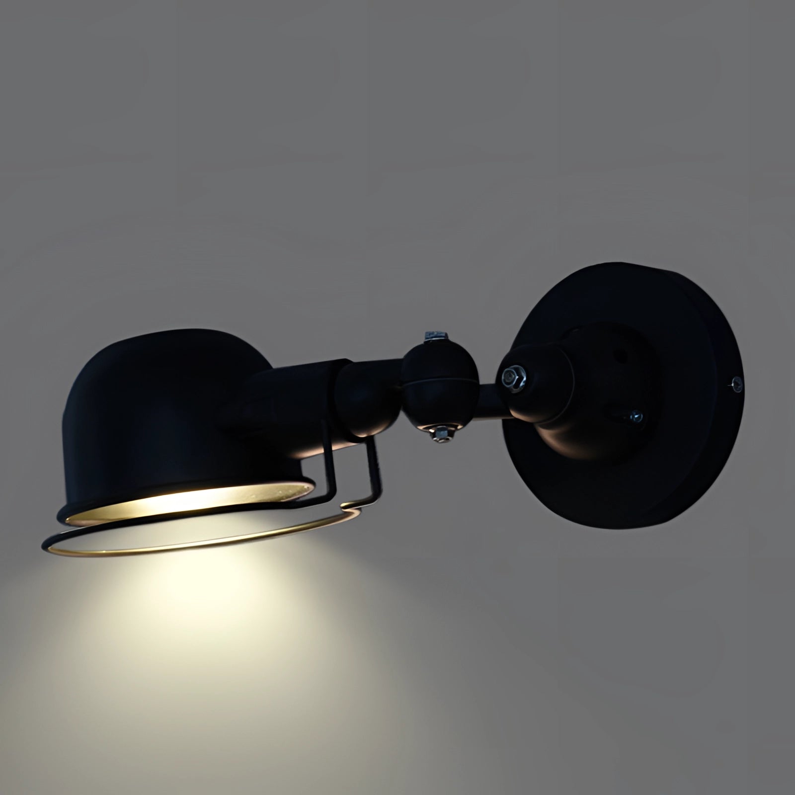 Modern matte black swing arm wall lamp with a short adjustable arm, featuring an industrial design. The lamp is made of metal and serves as a stylish and functional sconce for contemporary interiors.