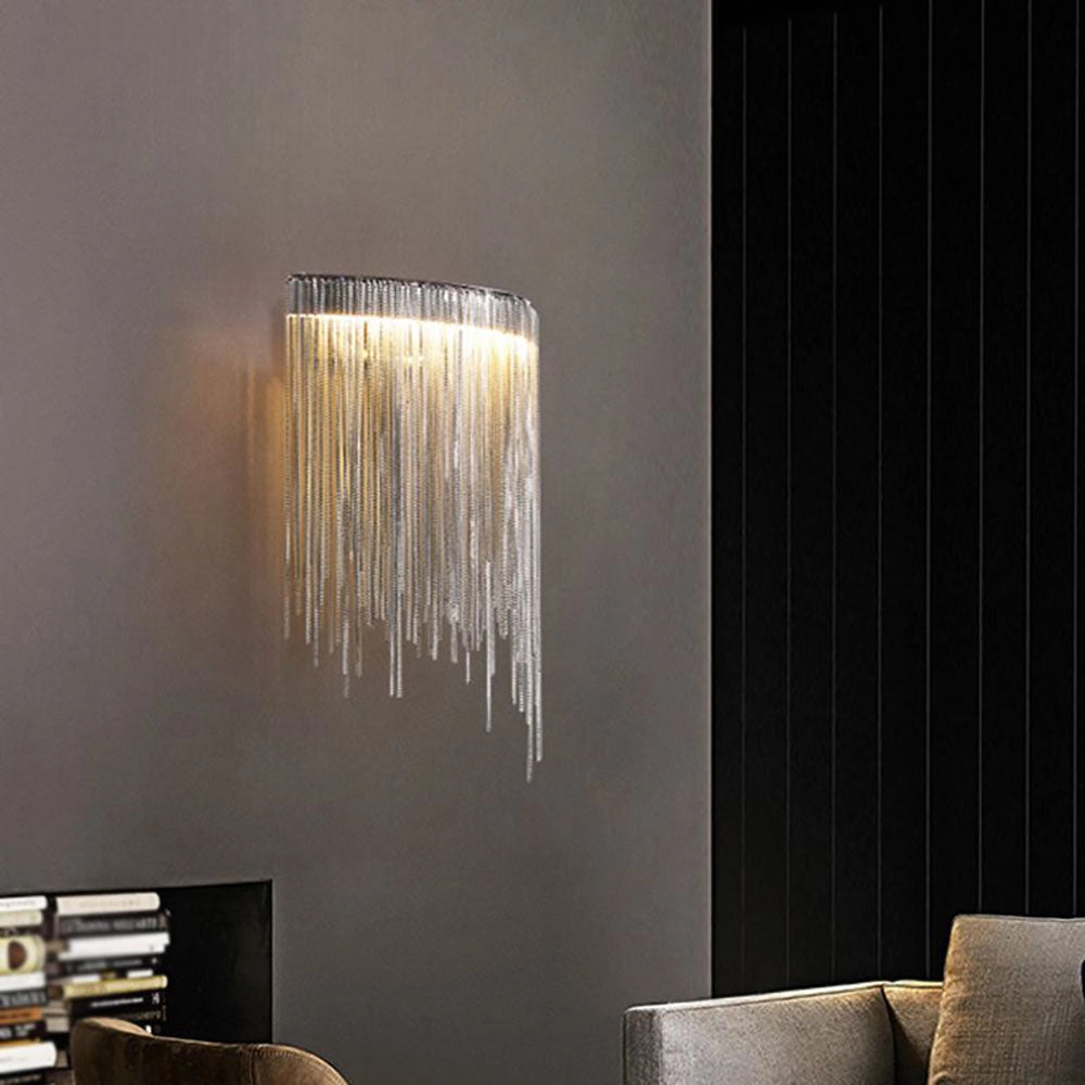 Modern metallic fringe chandelier hanging from the ceiling in a luxury contemporary interior setting, featuring a couch and wooden flooring with stylish decor elements.