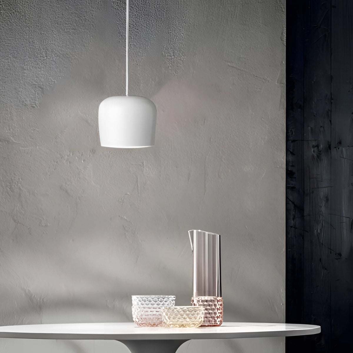 A modern minimalist bookshelf featuring a blue and white color scheme with a sleek rectangular design, surrounded by a grey lamp with a shade, glassware, and various decorative items on wooden flooring.