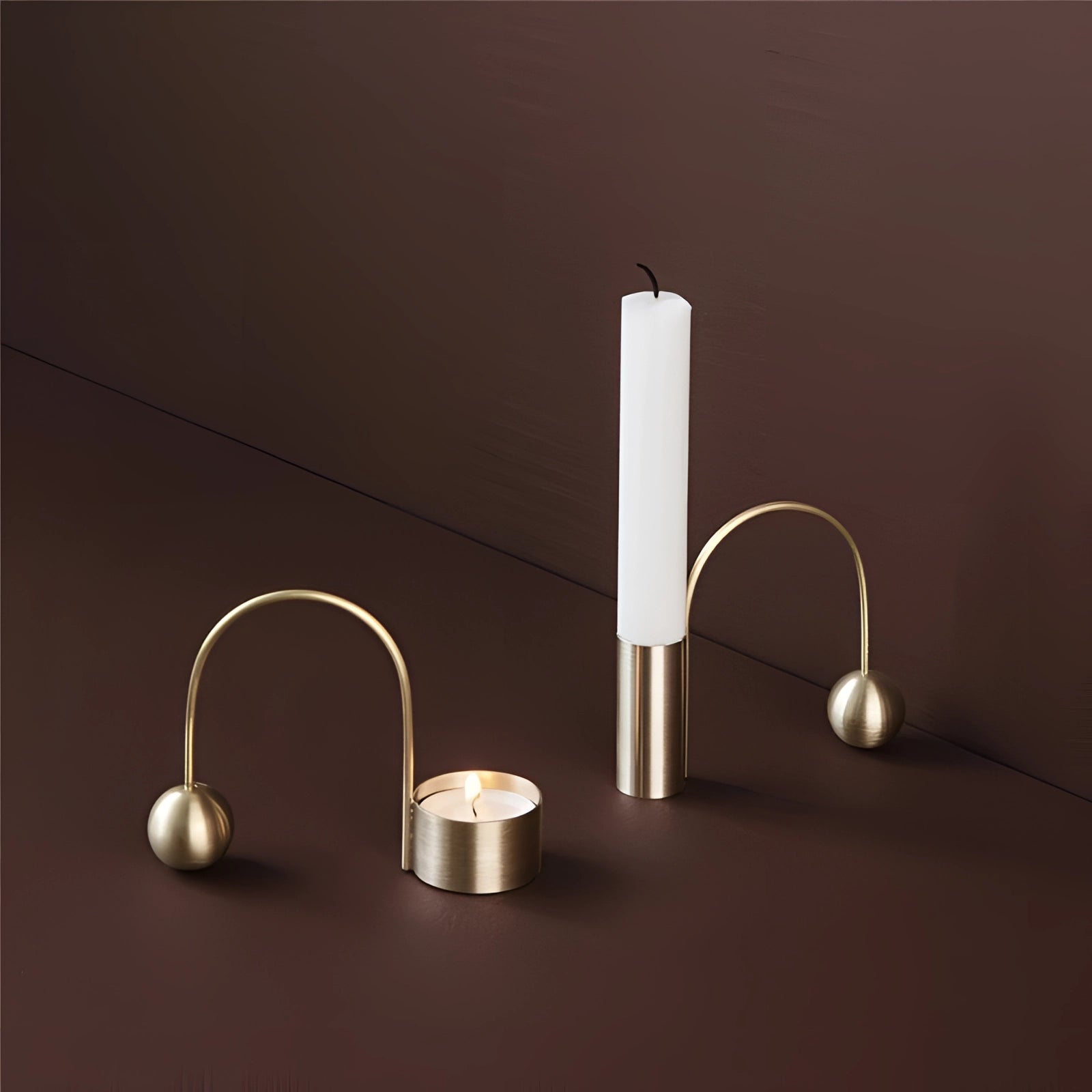 Modern minimalist brass candlestick in a unique design, placed on a wooden table, showcasing its artistic metal structure under soft lighting.