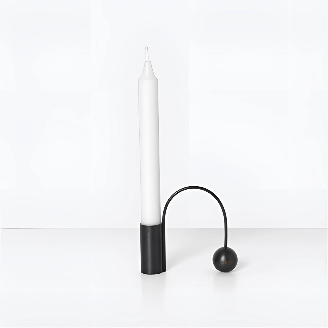 Modern minimalist black brass candlestick with a 1.5-inch height, featuring a unique and sleek design, displayed on a table in a still life setting.