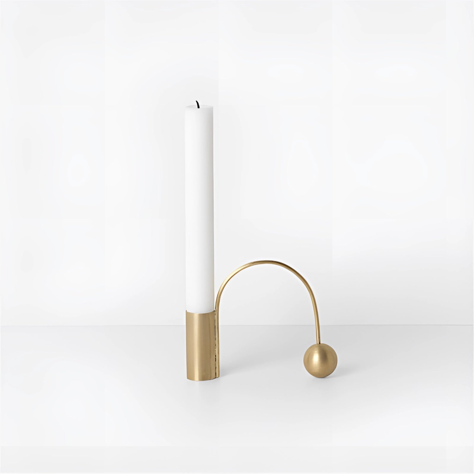 A gold modern minimalist brass candlestick, 1.5 inches tall, displayed on a wooden table with a simple, elegant design.