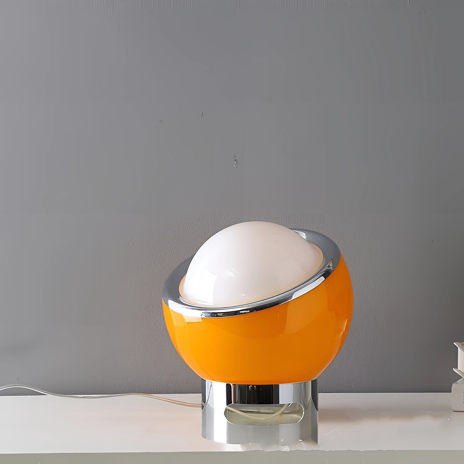 Modern Minimalist Circular LED Bedside Lamp with Sleek Metallic Base in Orange, displayed on a bedside table.