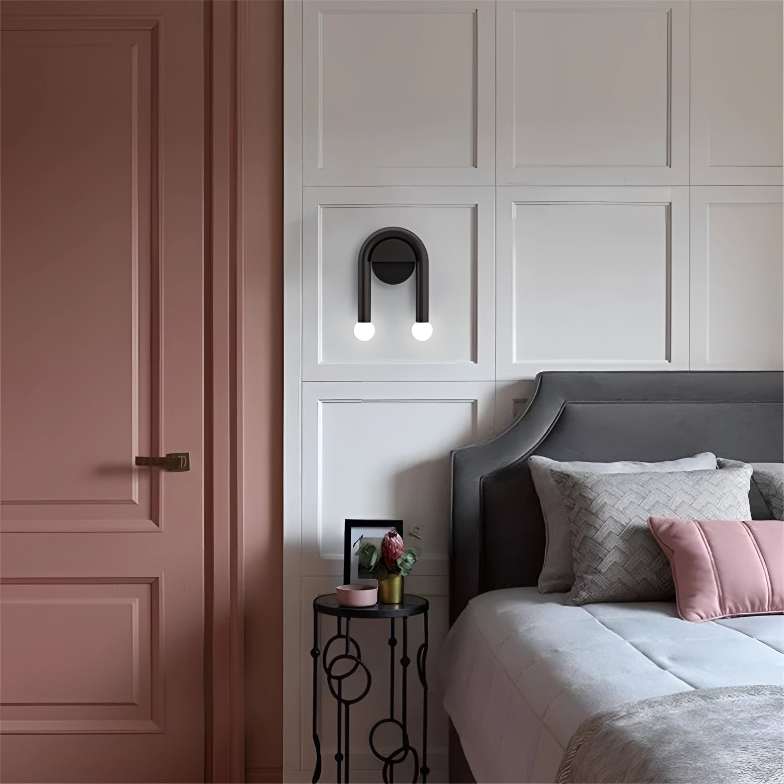 Modern minimalist LED dual wall lamp in black matte finish, installed on a grey wall above a wooden bed frame, providing energy-efficient lighting.
