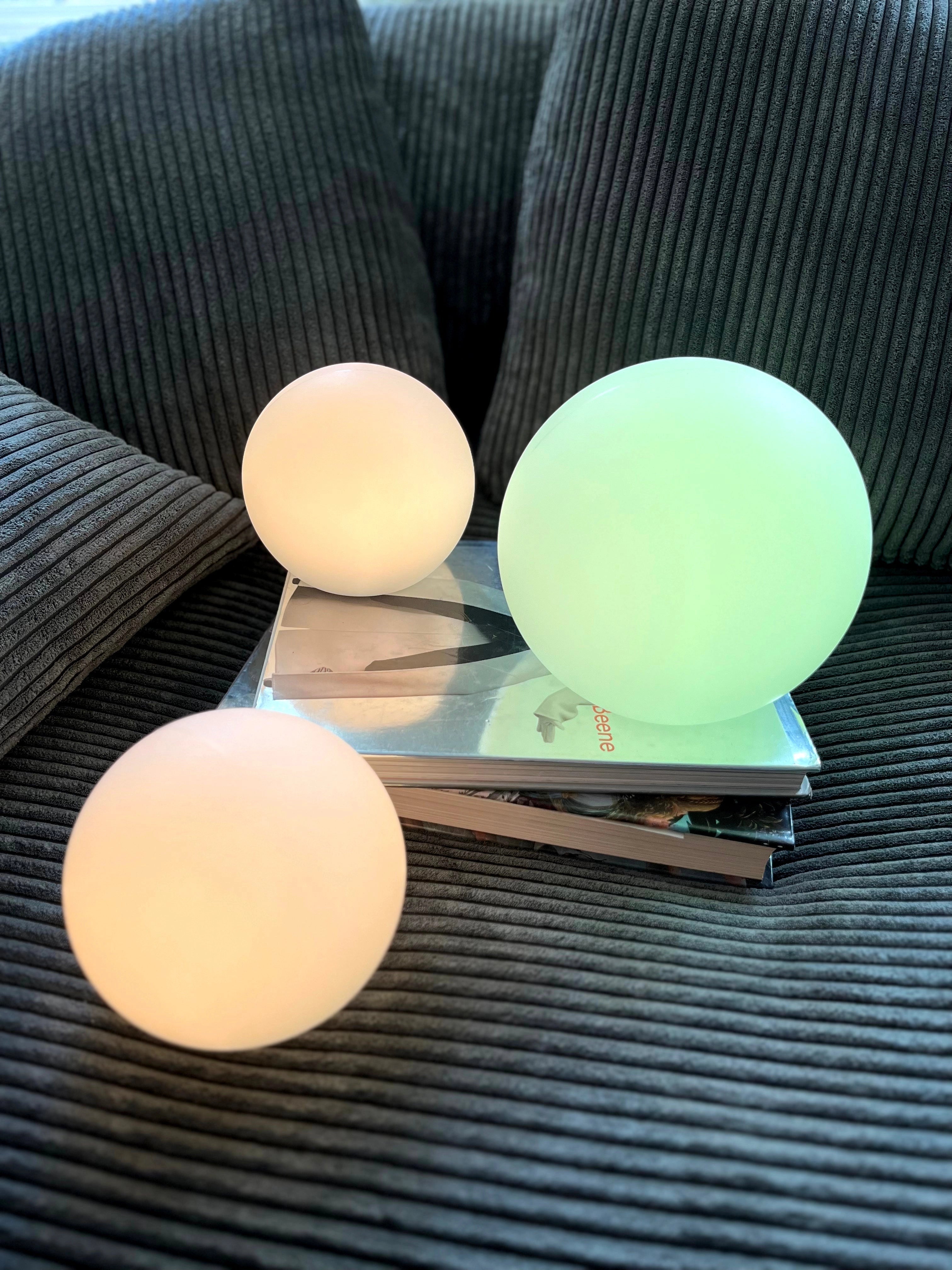 Modern minimalist LED globe lamp on a wooden table, showcasing its cordless and rechargeable design, ideal for bedside use.