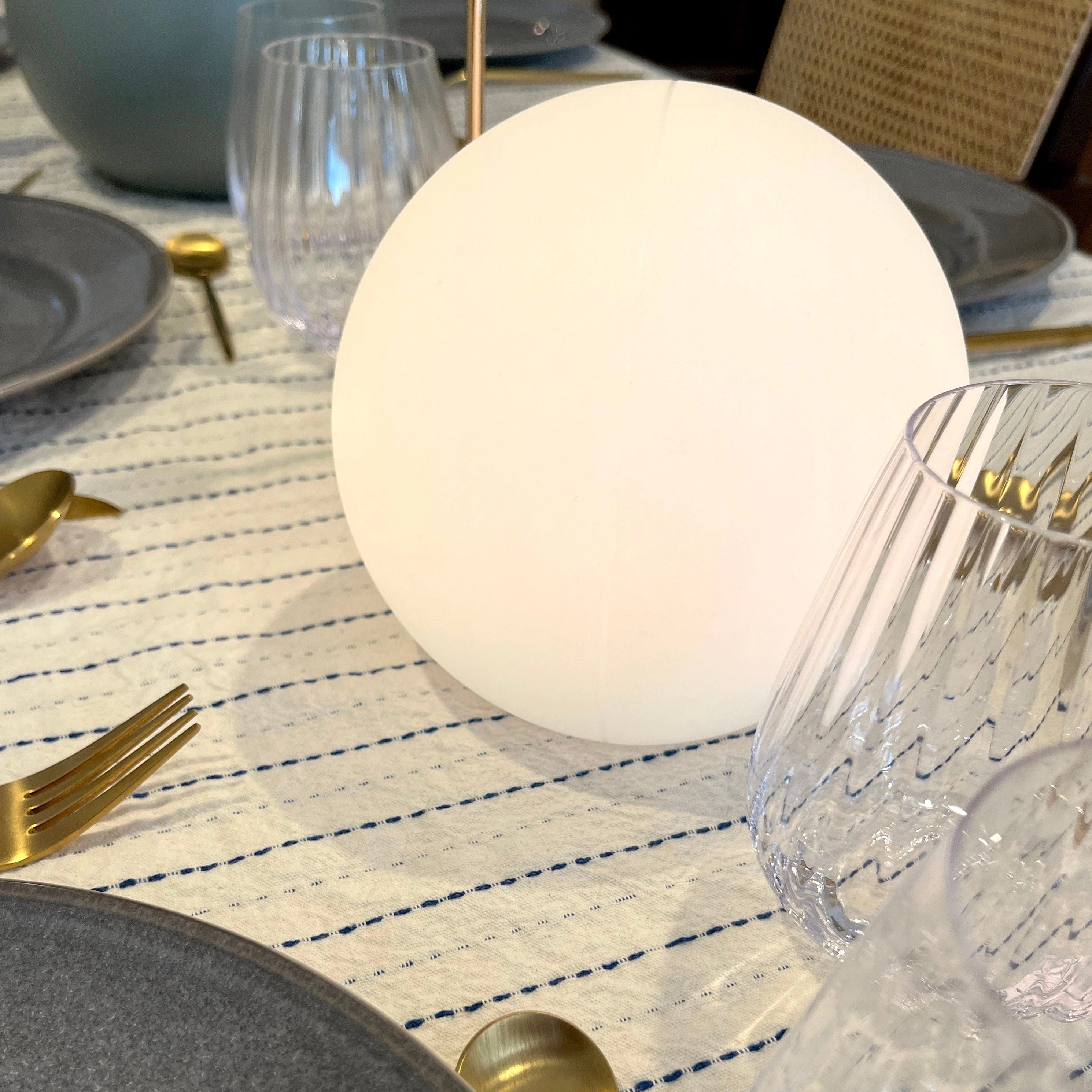 Modern Minimalist LED Globe Lamp on a table next to dishware, including a plate, cutlery, and drinkware.
