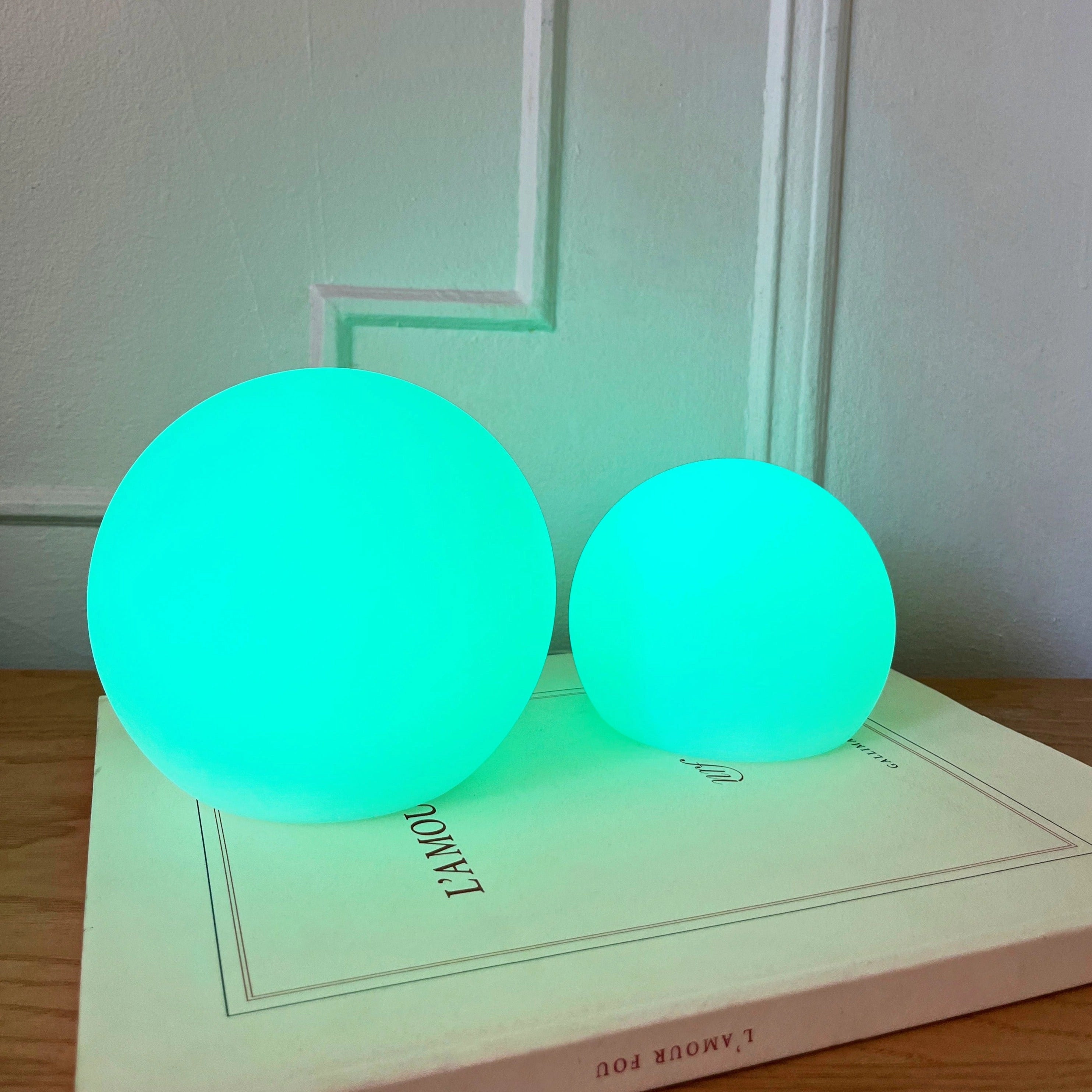 Modern minimalist LED globe lamp placed on a table, featuring a sleek cordless design with a soft azure glow.
