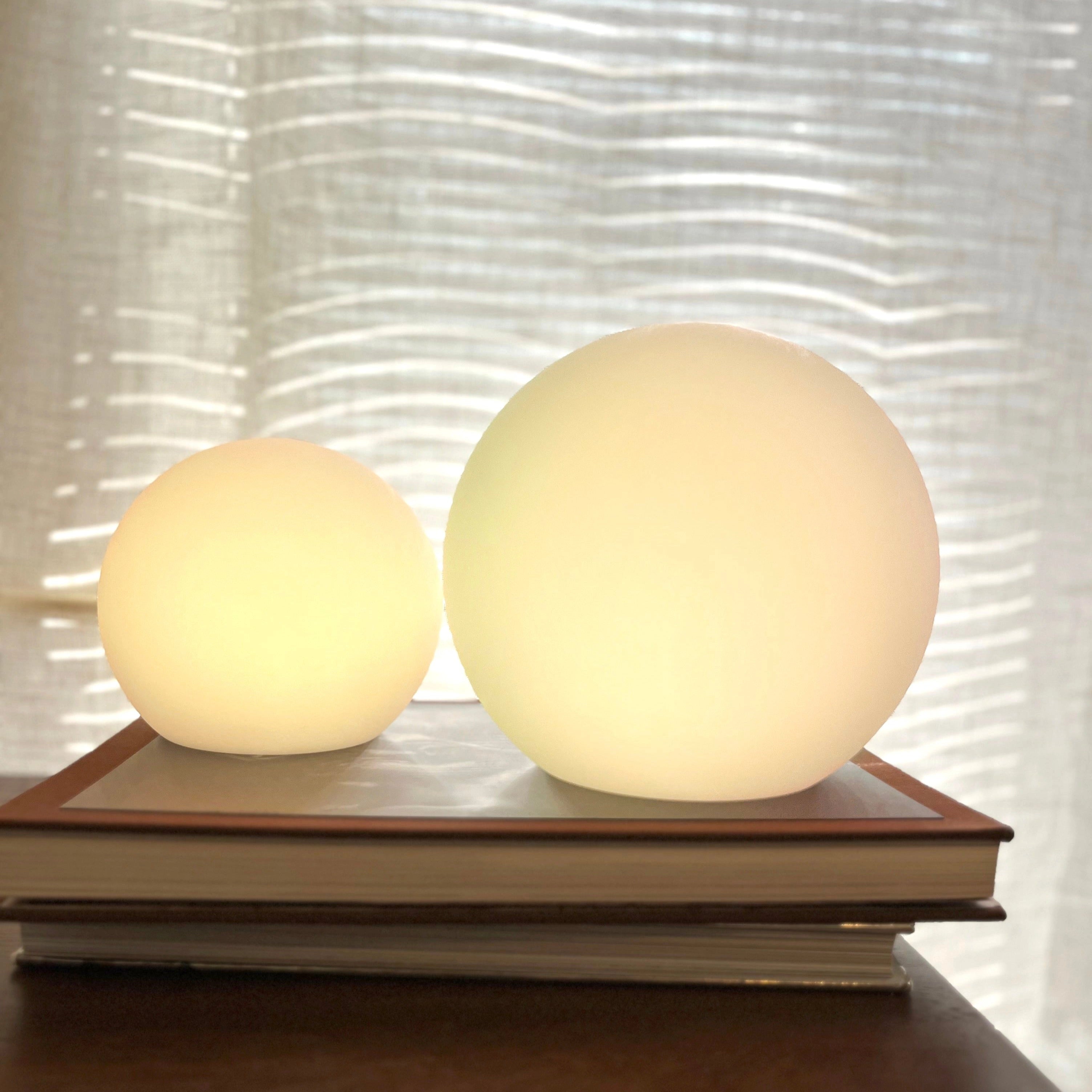 Modern Minimalist LED Globe Lamp on a wooden table with beige wall background, cordless and rechargeable bedside light.