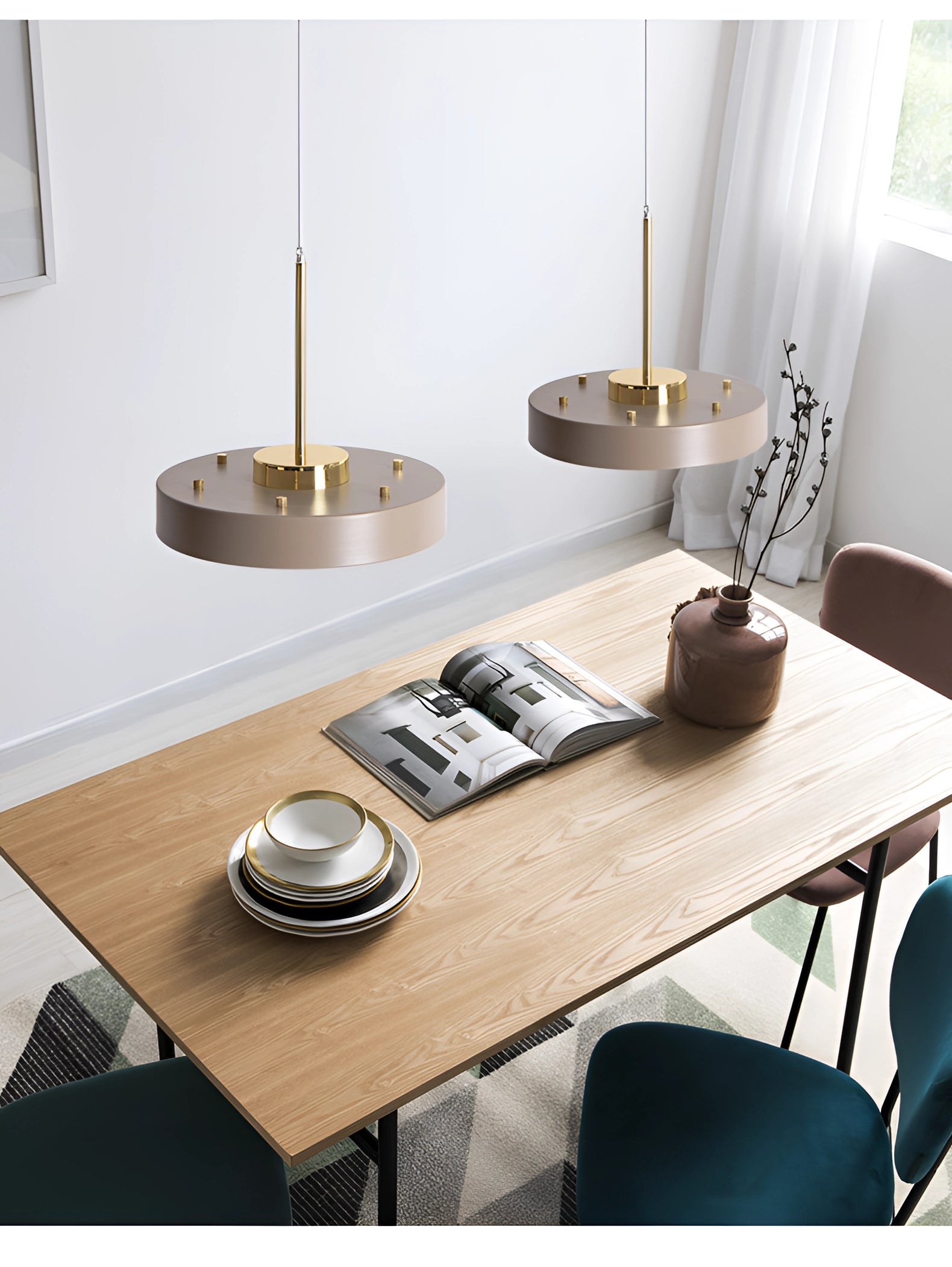 Modern minimalist LED pendant lights in gold and white hanging above a wooden table set with tableware and serveware.
