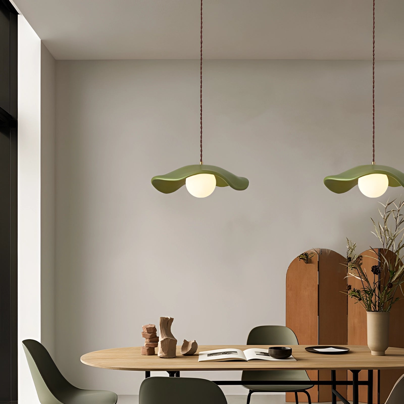 Modern minimalist LED pendant light with dual spheres hanging from the ceiling in a stylish interior setting, featuring wooden furniture, a table, chairs, a plant, and a well-designed wall.