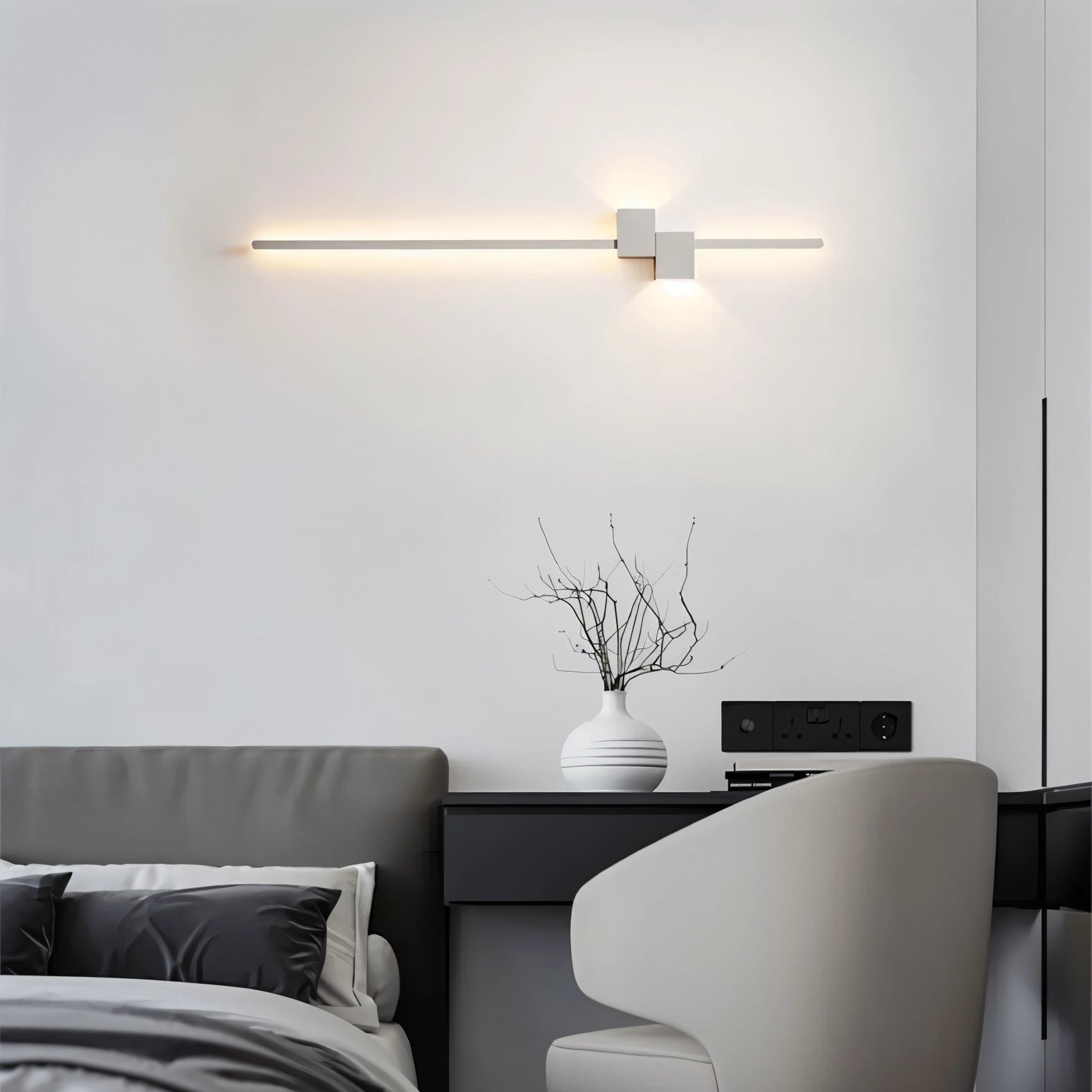 Modern minimalist LED wall light mounted on a bedroom wall, illuminating a contemporary interior space with a couch and small table nearby, enhancing the room's comfort and style.