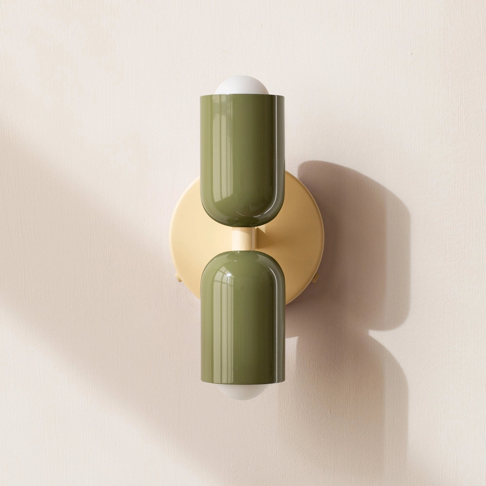 Modern minimalist LED wall sconce featuring a geometric dual head design, shown mounted on a beige wall with a sleek metal finish.