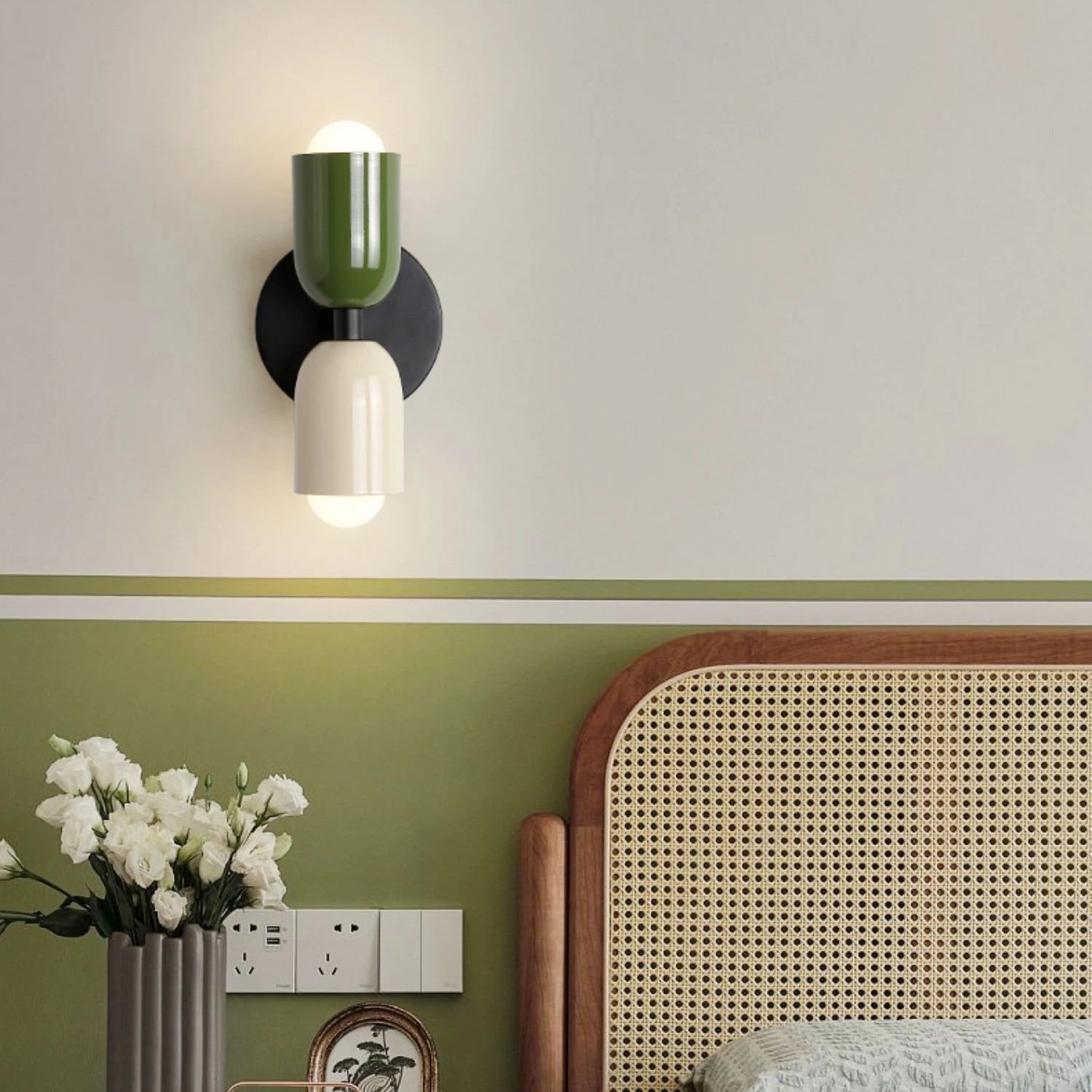 Modern minimalist geometric dual head LED wall sconce mounted on a grey wall above wooden shelving, with decorative plants and a vase adding a touch of nature to the interior design.