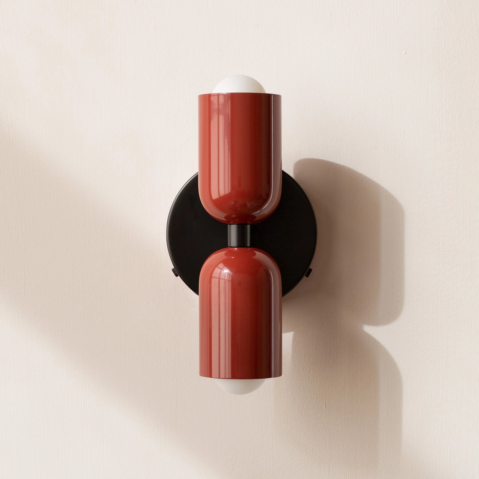 A modern minimalist LED wall sconce with a geometric design featuring dual heads in a striking red and black color scheme.