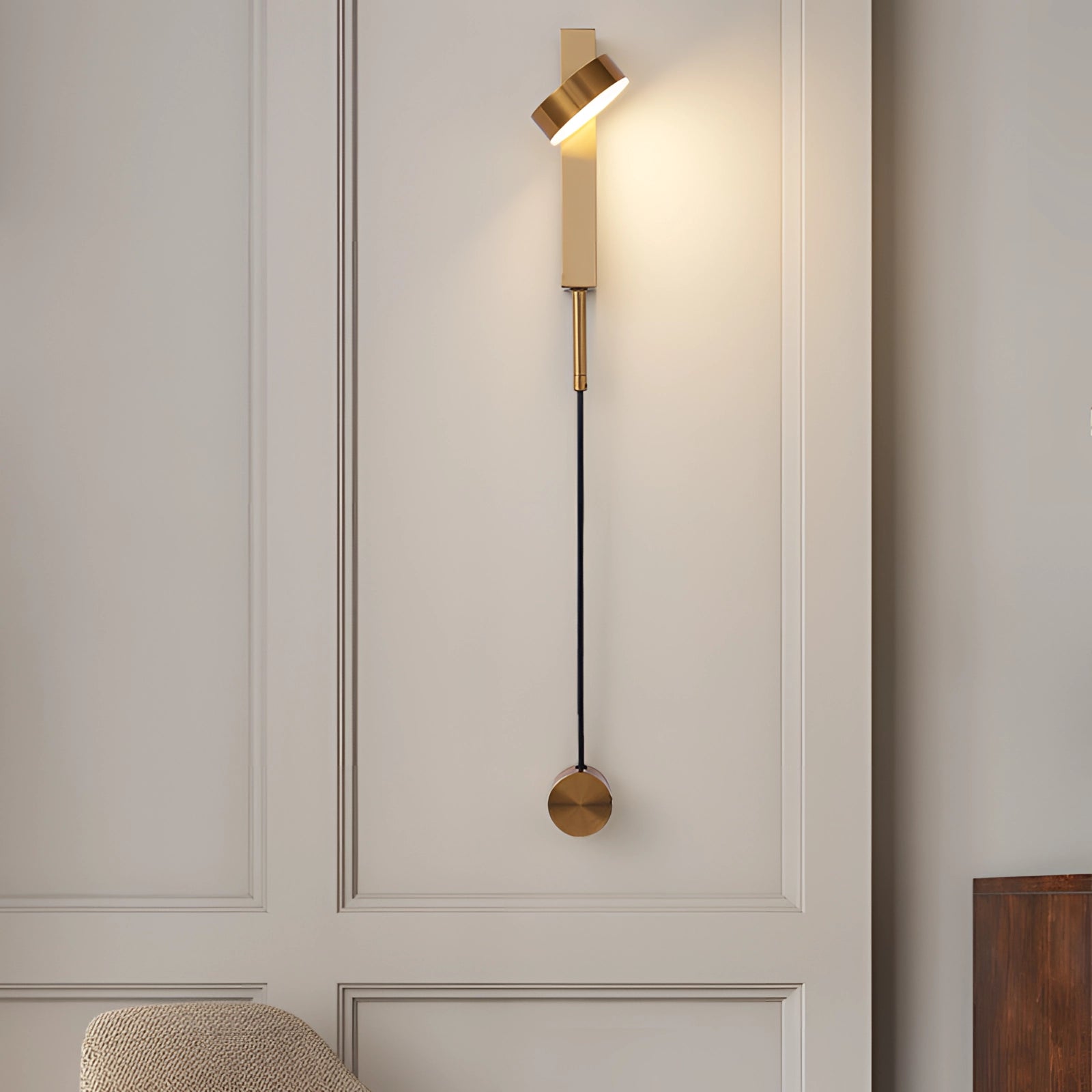 Modern minimalist LED wall sconce in a gold finish mounted on a wooden wall, showcasing a rectangular design with a streamlined appearance, providing white light at 5000K suitable for bedrooms, designed for 110 V-120 V electrical systems typical in USA and Canada.