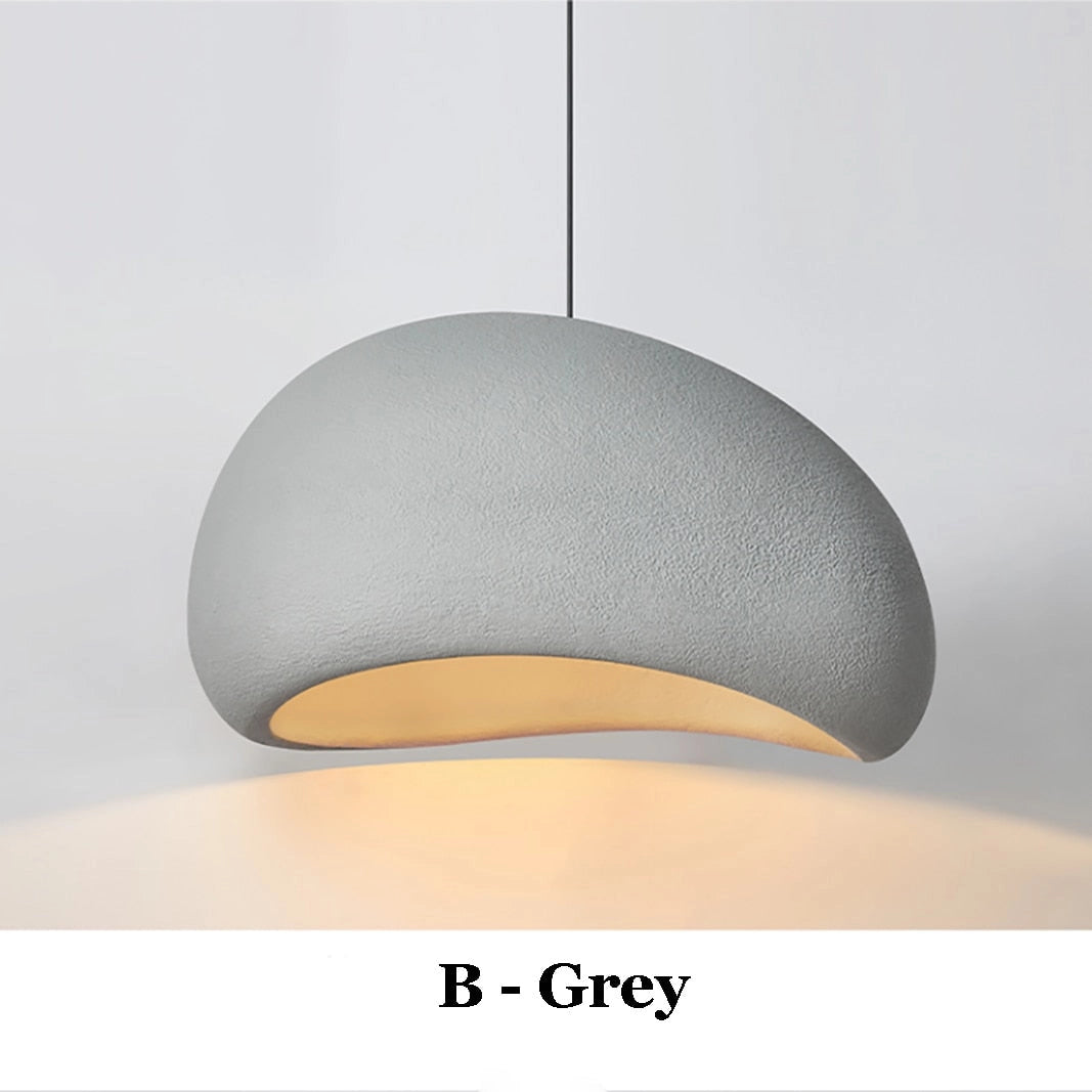 A modern minimalist pendant light in gray with a sleek cylindrical design, suitable for Scandinavian kitchen lighting. The light fixture is suspended from the ceiling, emitting a warm white glow.