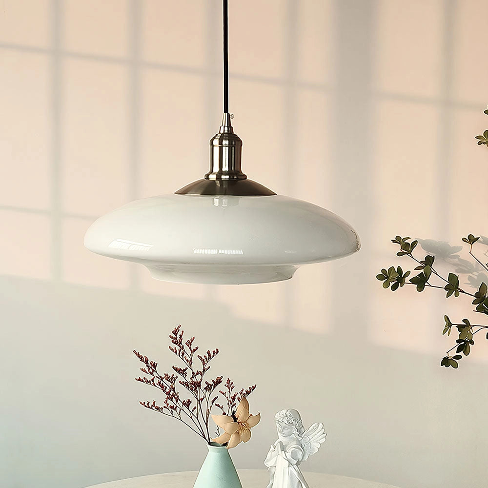 Modern minimalist pendant light with a frosted glass shade, featuring an adjustable height design, suspended from the ceiling in a white and light-toned setting, surrounded by decorative twigs and plants.
