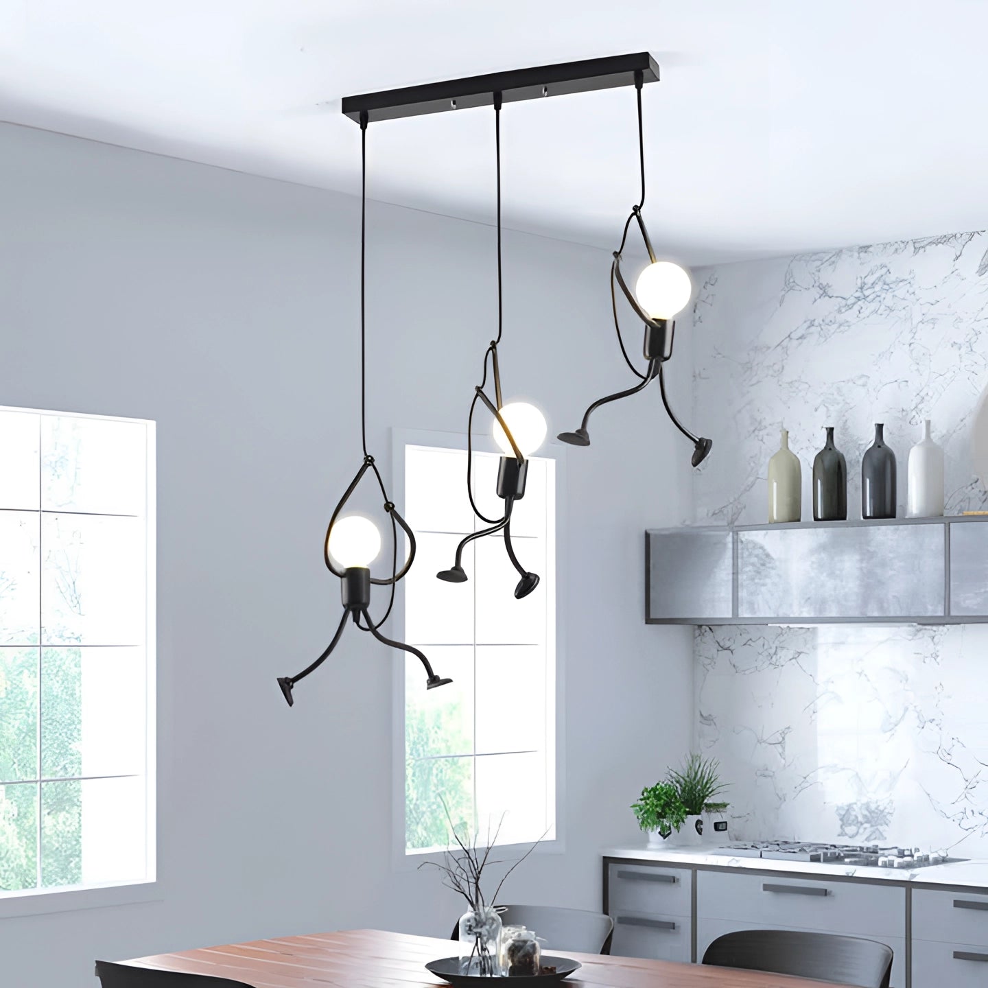 Modern minimalist pendant light with three lights in a beam, hanging over a wooden table in a well-lit interior with grey walls, a plant, and large windows.