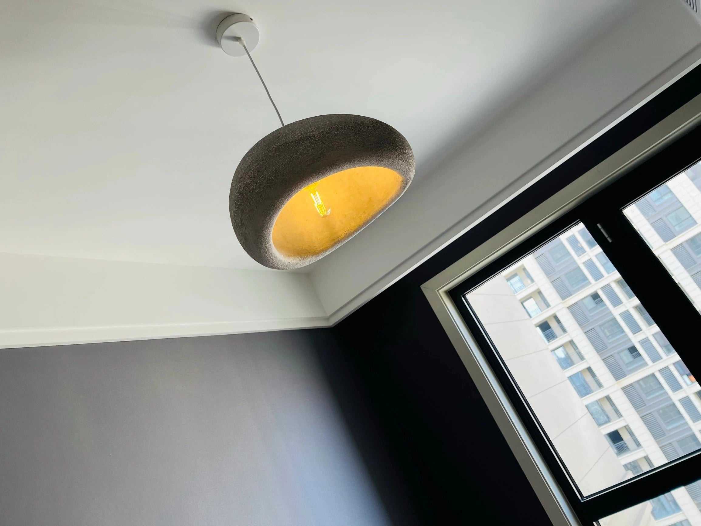 Modern minimalist pendant lights hanging from the ceiling, featuring a sleek design with circular shades, illuminating a Scandinavian-style kitchen interior.