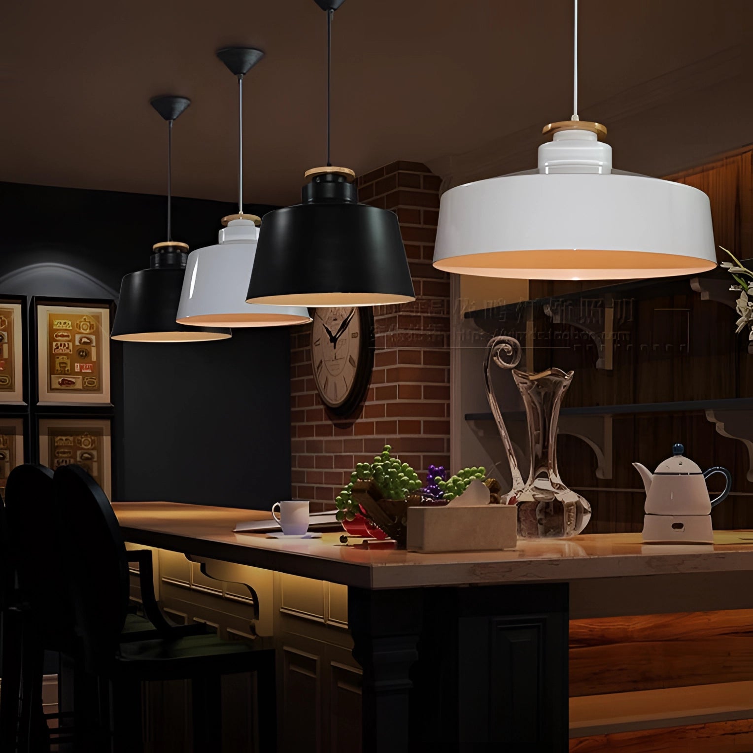 Modern minimalist pendant lights in black and white Scandinavian design hanging above a wooden kitchen table with cabinetry and shelving in the background, showcasing a sleek and contemporary interior design.