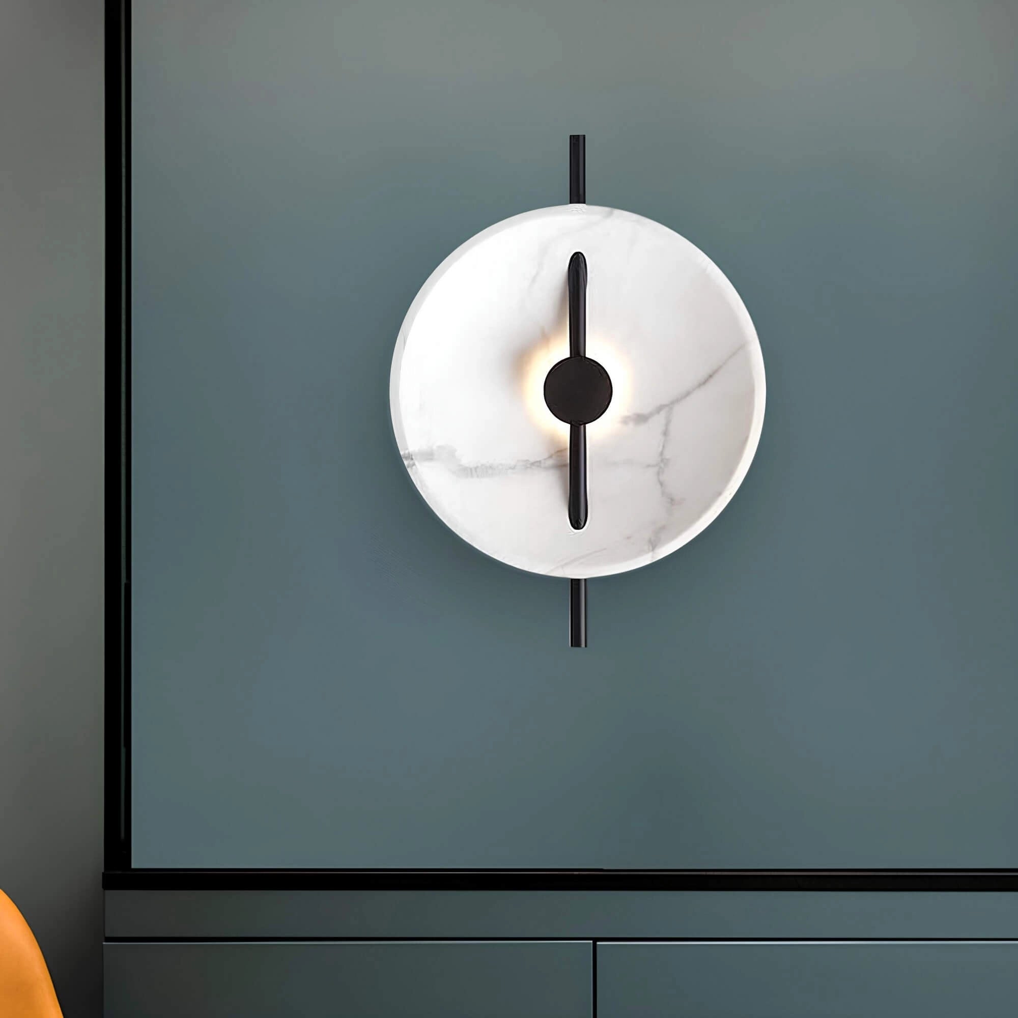 Modern minimalist silver round wall clock with a sleek design, mounted on a wooden background in a room setting.