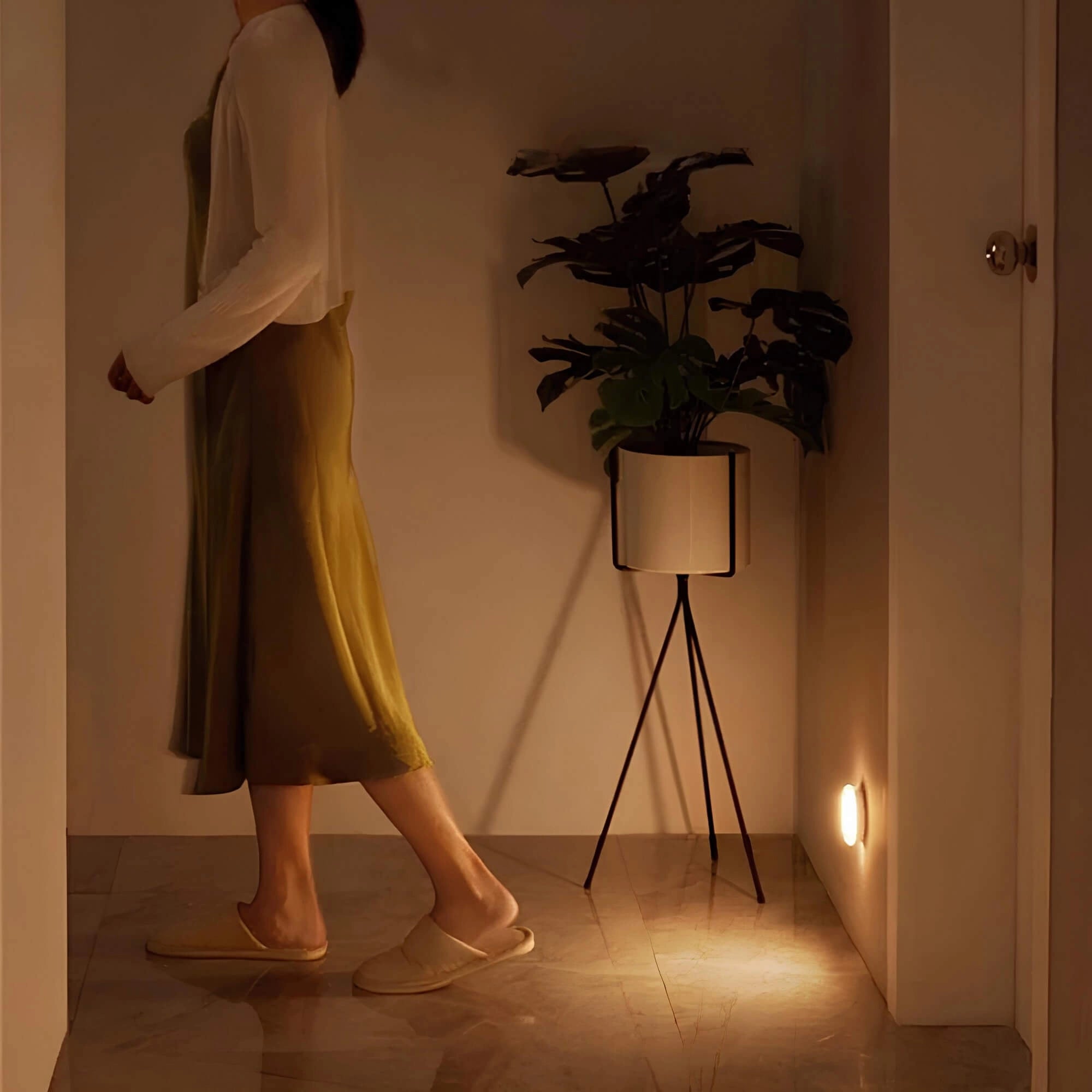 Modern minimalist wall lamp with warm white LED light, mounted on a wall, providing stylish decor in a room with wooden flooring and contemporary design elements.