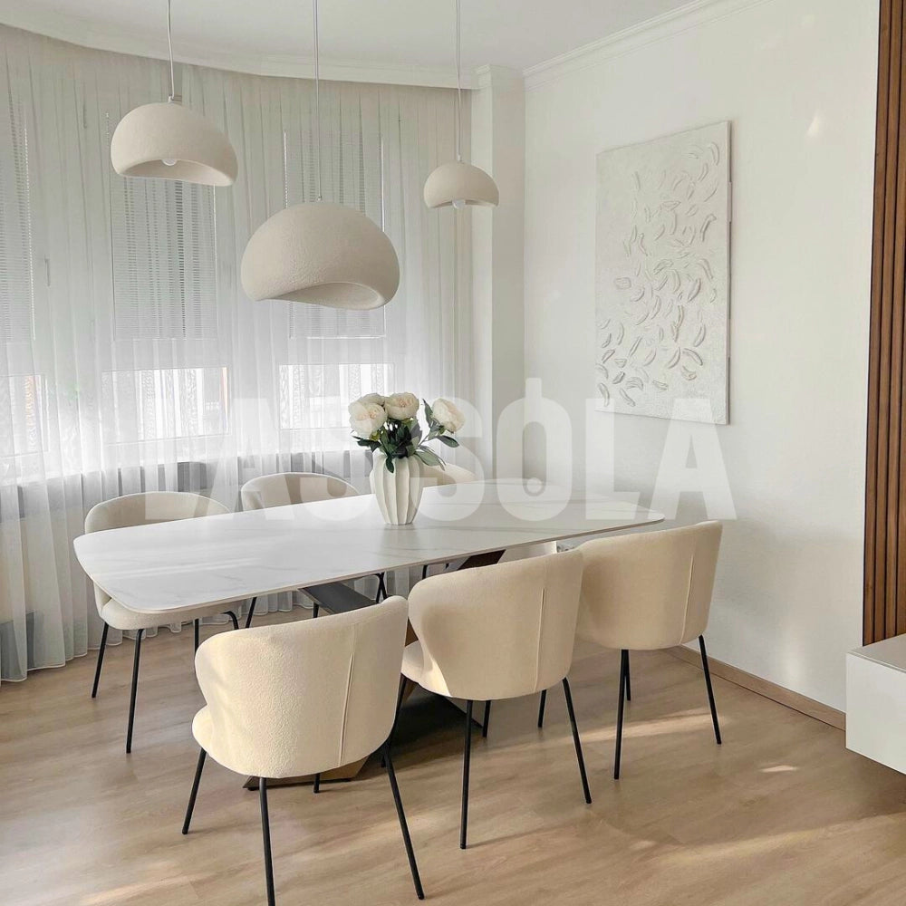 Modern minimalist white dome pendant light hanging above a wooden table, with elegant decor featuring contemporary furniture including chairs and a well-designed interior space.