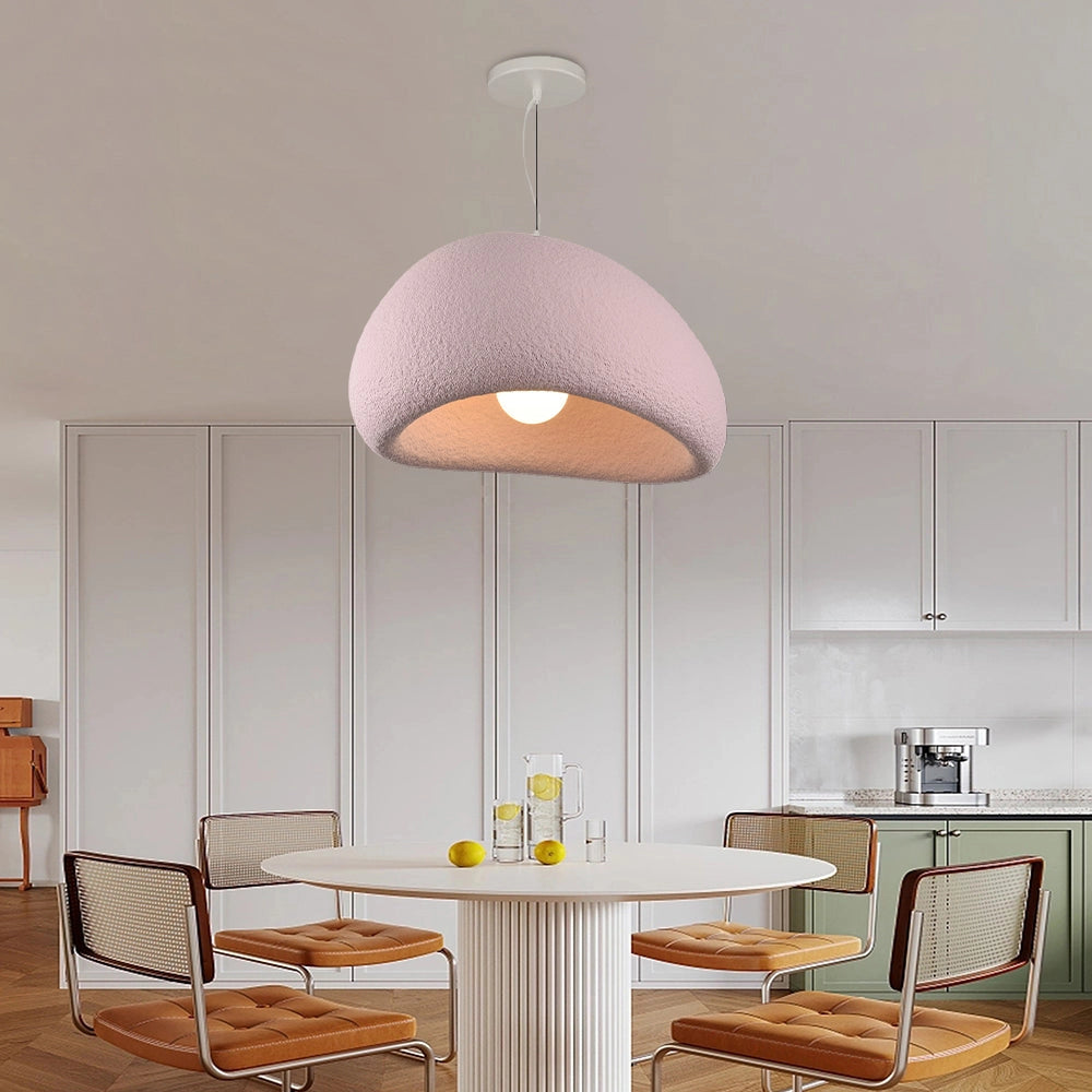 Modern minimalist white dome pendant light hanging above a dining area with a wooden table and chairs, featuring elegant interior design elements and pink accents, set on a hardwood floor.