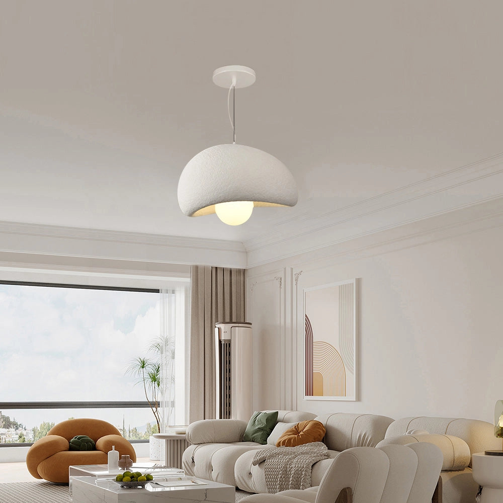 Modern minimalist white dome pendant light hanging in an elegantly decorated living room featuring a couch, wooden elements, and a table, creating a cozy and stylish interior design.