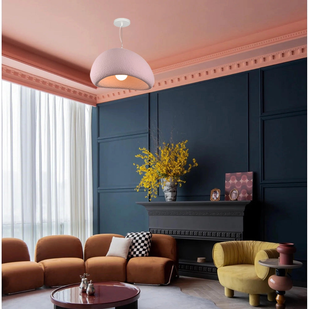 Modern minimalist white dome pendant light with a 23.6-inch pink accent, hanging above a living room setting featuring a couch, wooden table, and houseplants, emphasizing elegant decor and interior design.