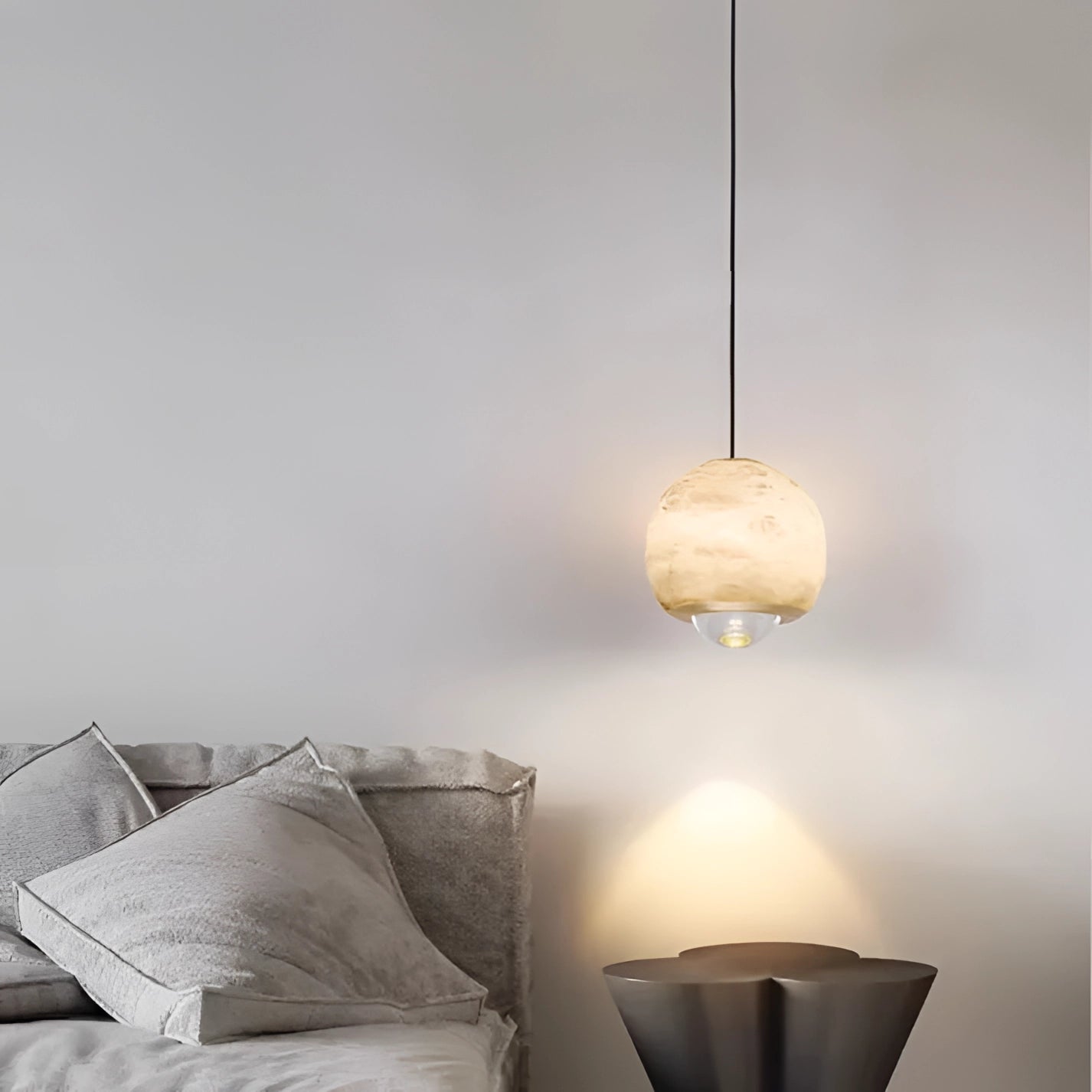 Modern minimalist white spherical pendant light with wooden accents, hanging from the ceiling in a stylish bedroom interior.