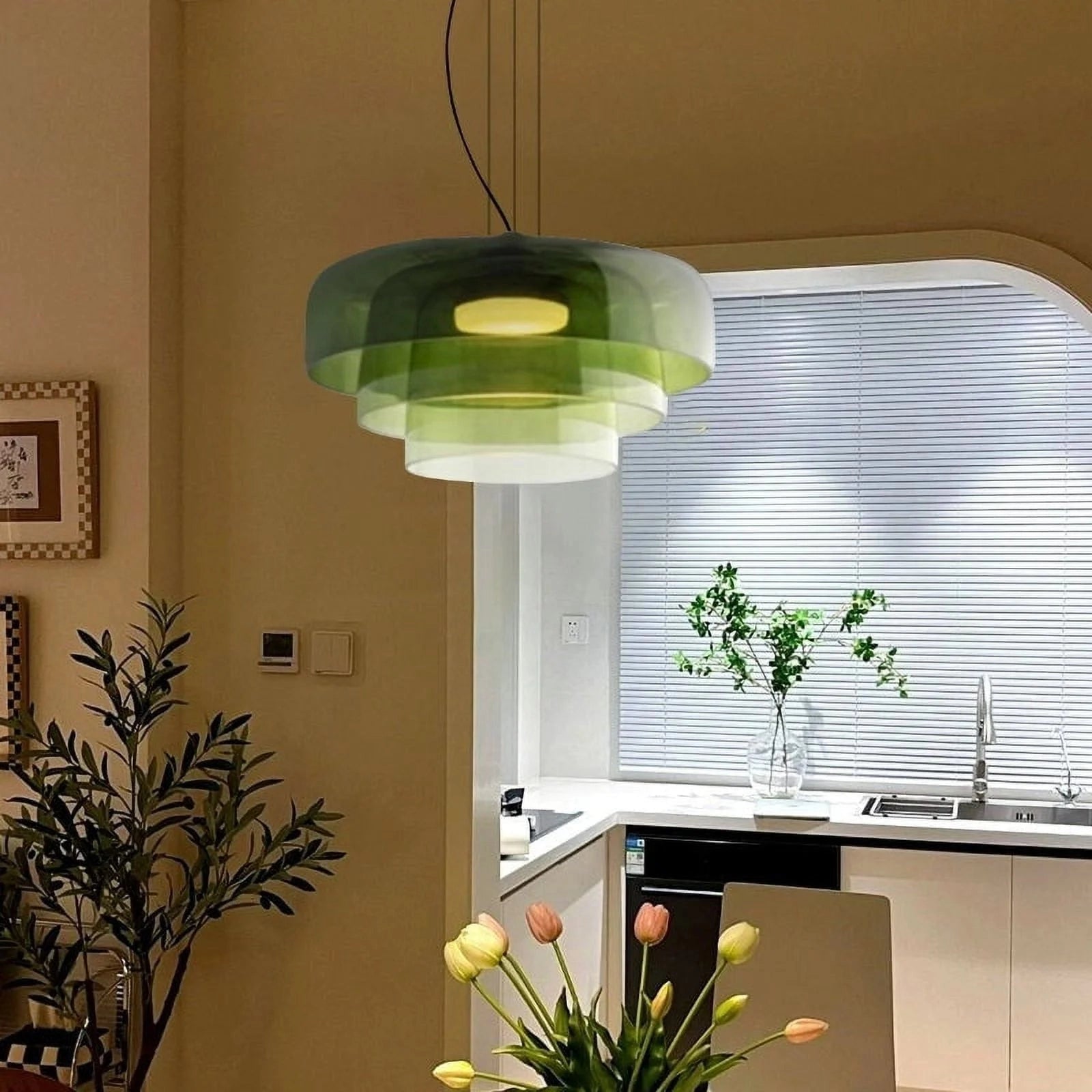 Modern multi-colored glass pendant light hanging in a stylish interior setting with green houseplants and decorative flowers.