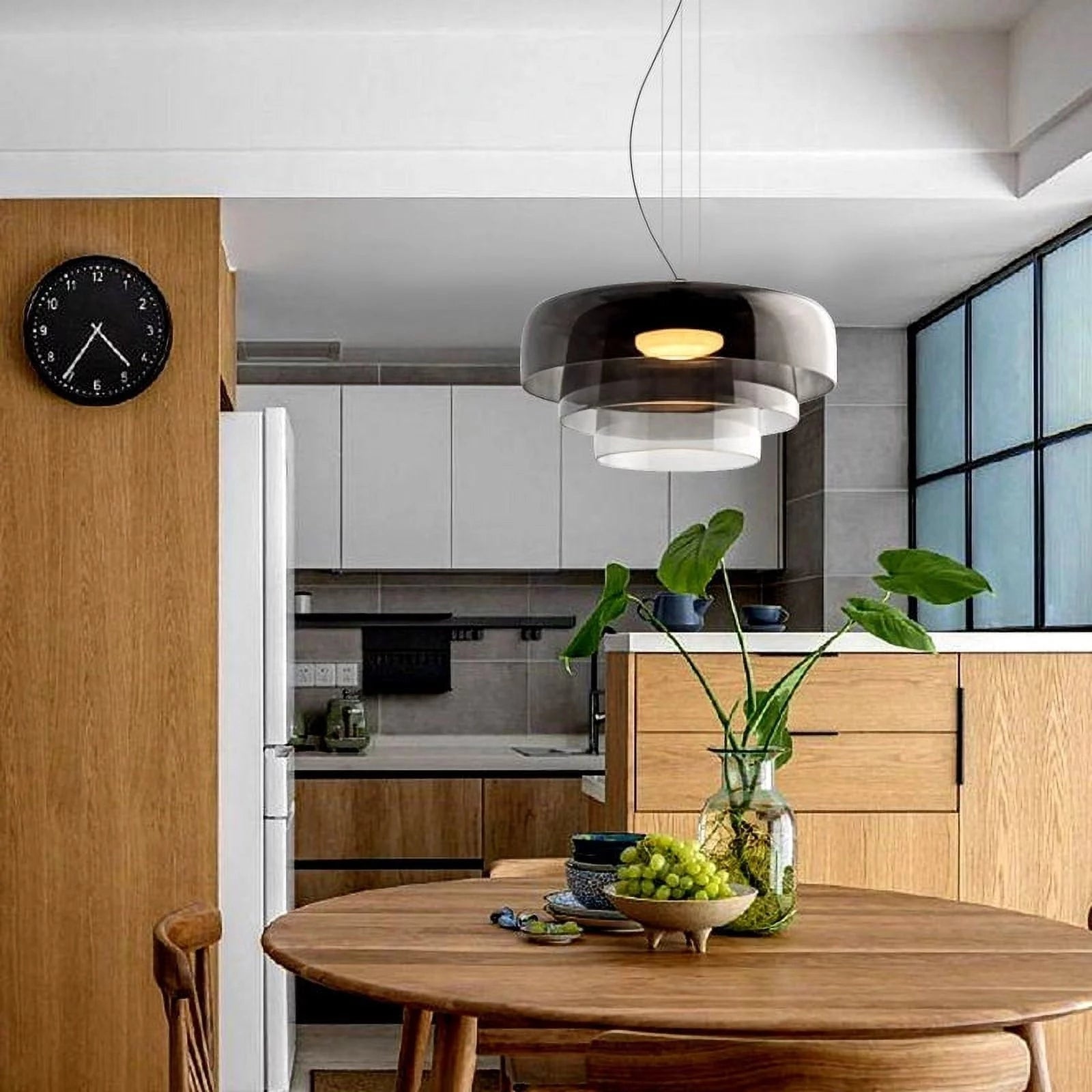 Modern multi-colored glass pendant light hanging above a wooden table with houseplants and a flowerpot in a contemporary interior design setting.