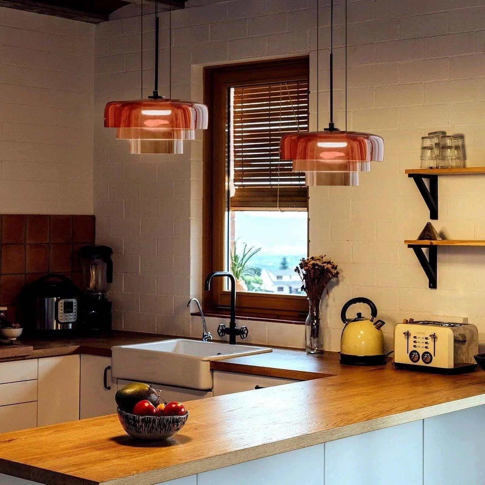 Modern multi-colored glass pendant light hanging above a kitchen countertop with a sink, cabinetry, a plant, and kitchen appliances.